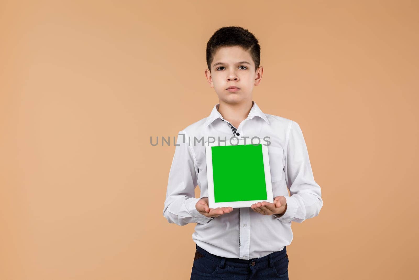 Little boy with tablet on light yellow studio background. by erstudio
