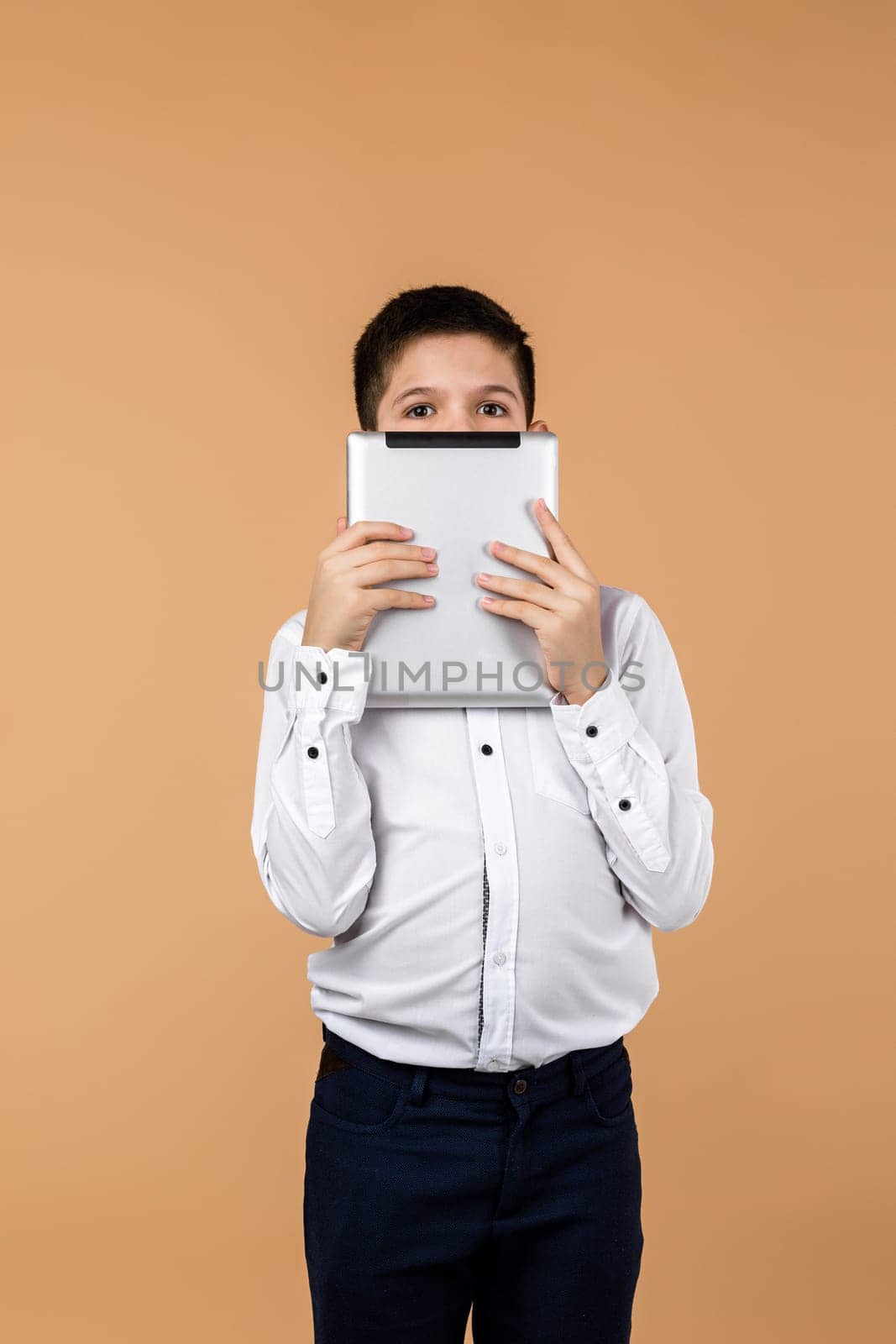 Emotional schoolboy holding digital tablet in front of his face. the child is afraid of the real world and lives in a virtual world