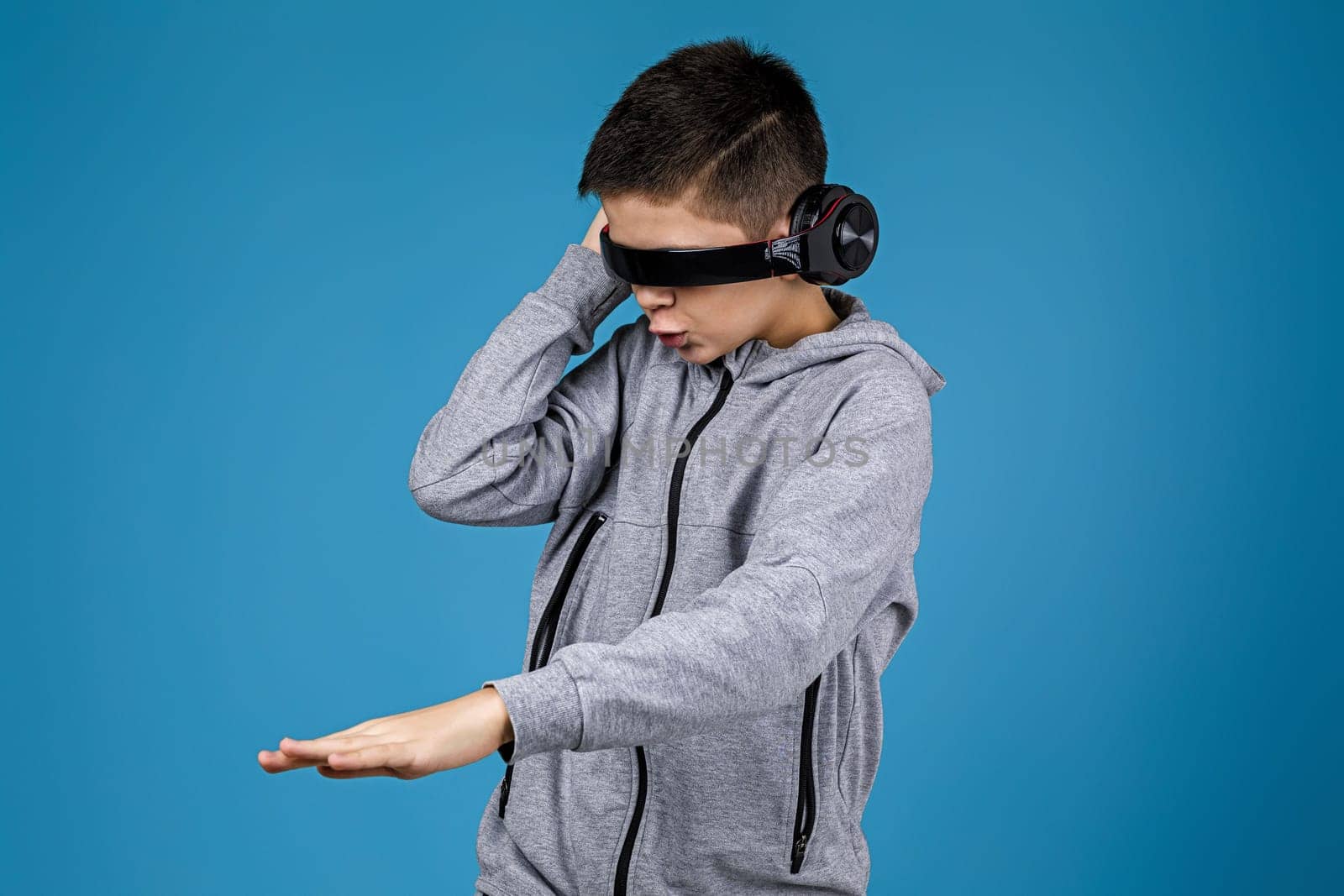 Happy child boy enjoys listens to music in headphones over blue background. boy dancing