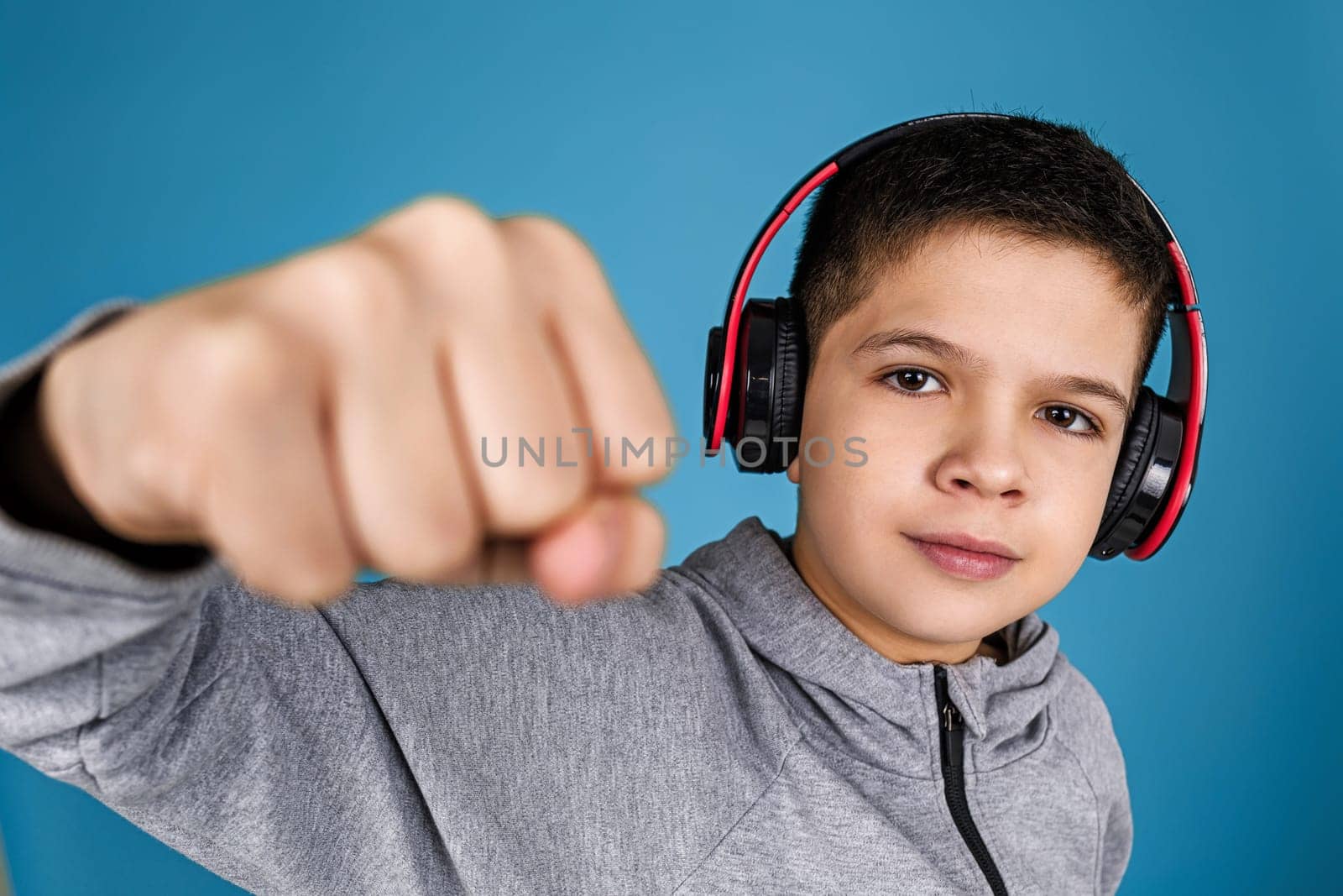 child boy enjoys listens to music in headphones over blue background