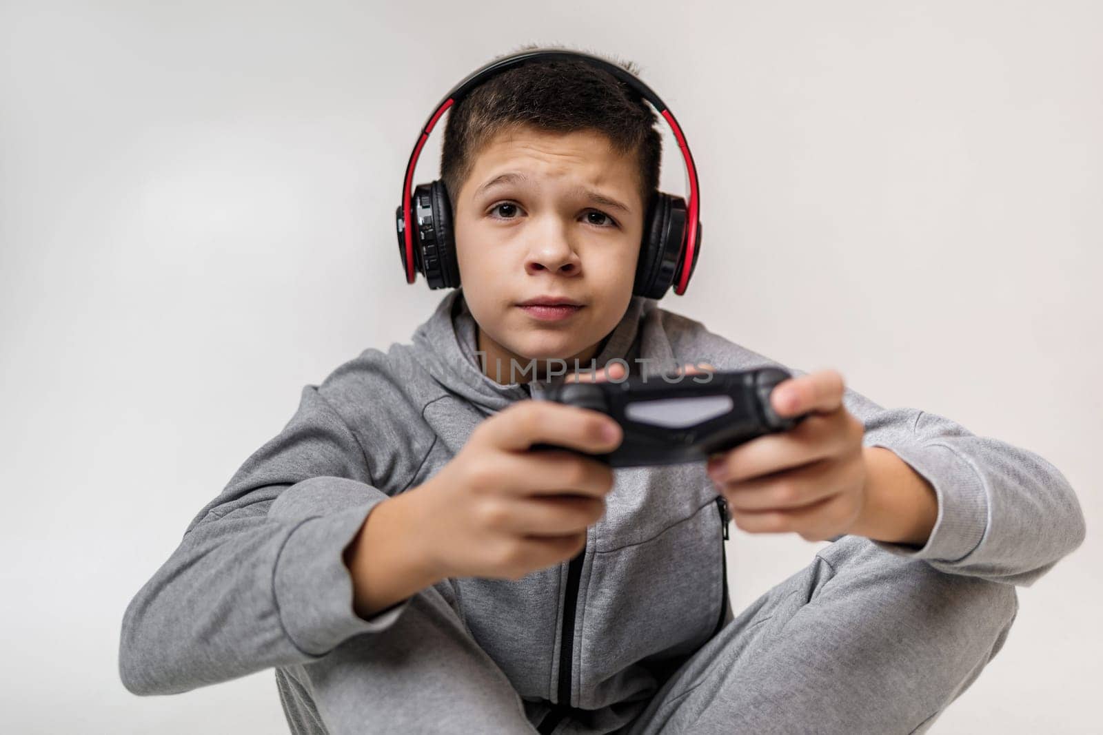 concentrated child boy playing video games over gray background. young gamer playing with game console