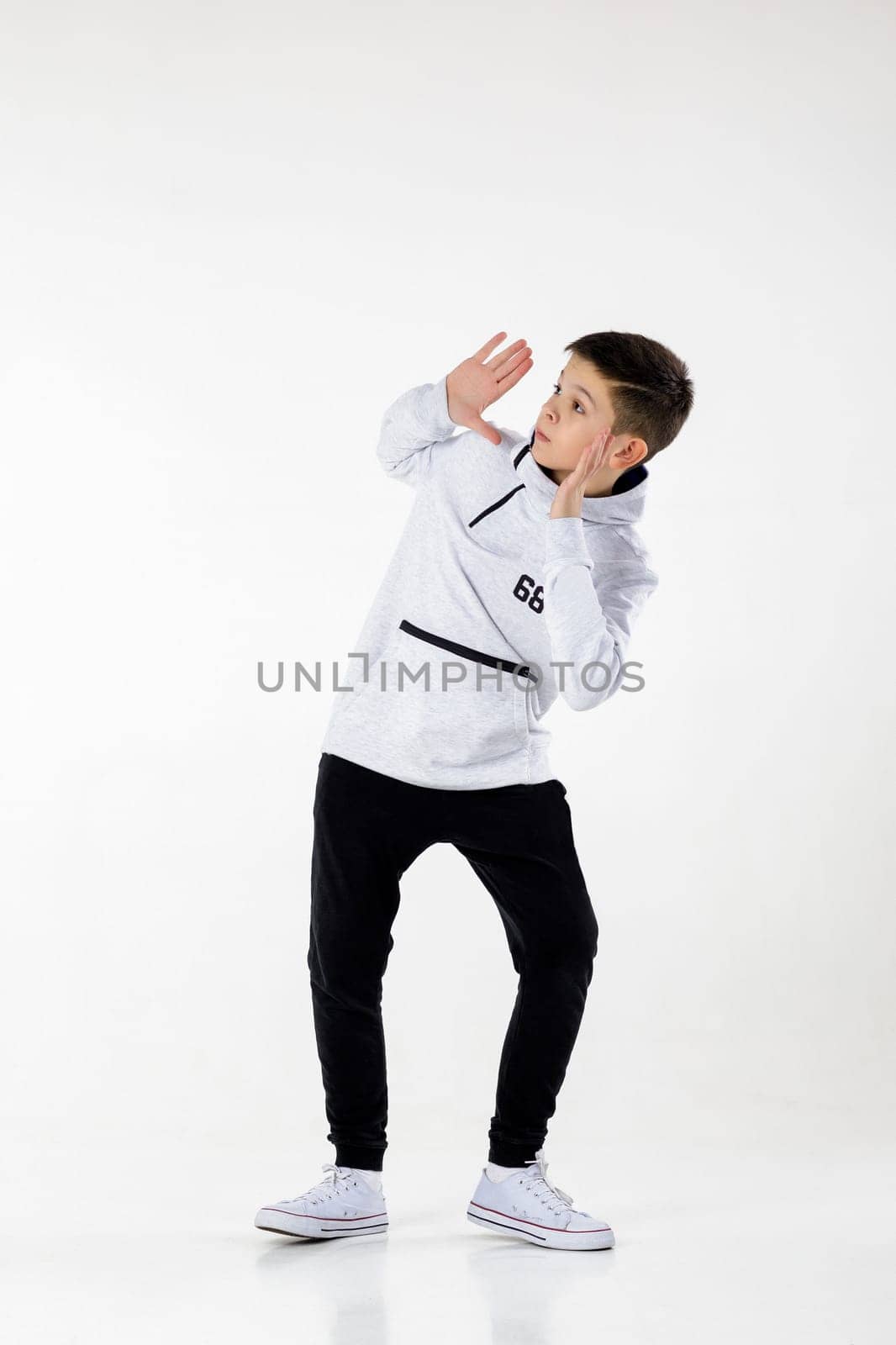 Little hip-hop boy dancing on white studio background. modern style