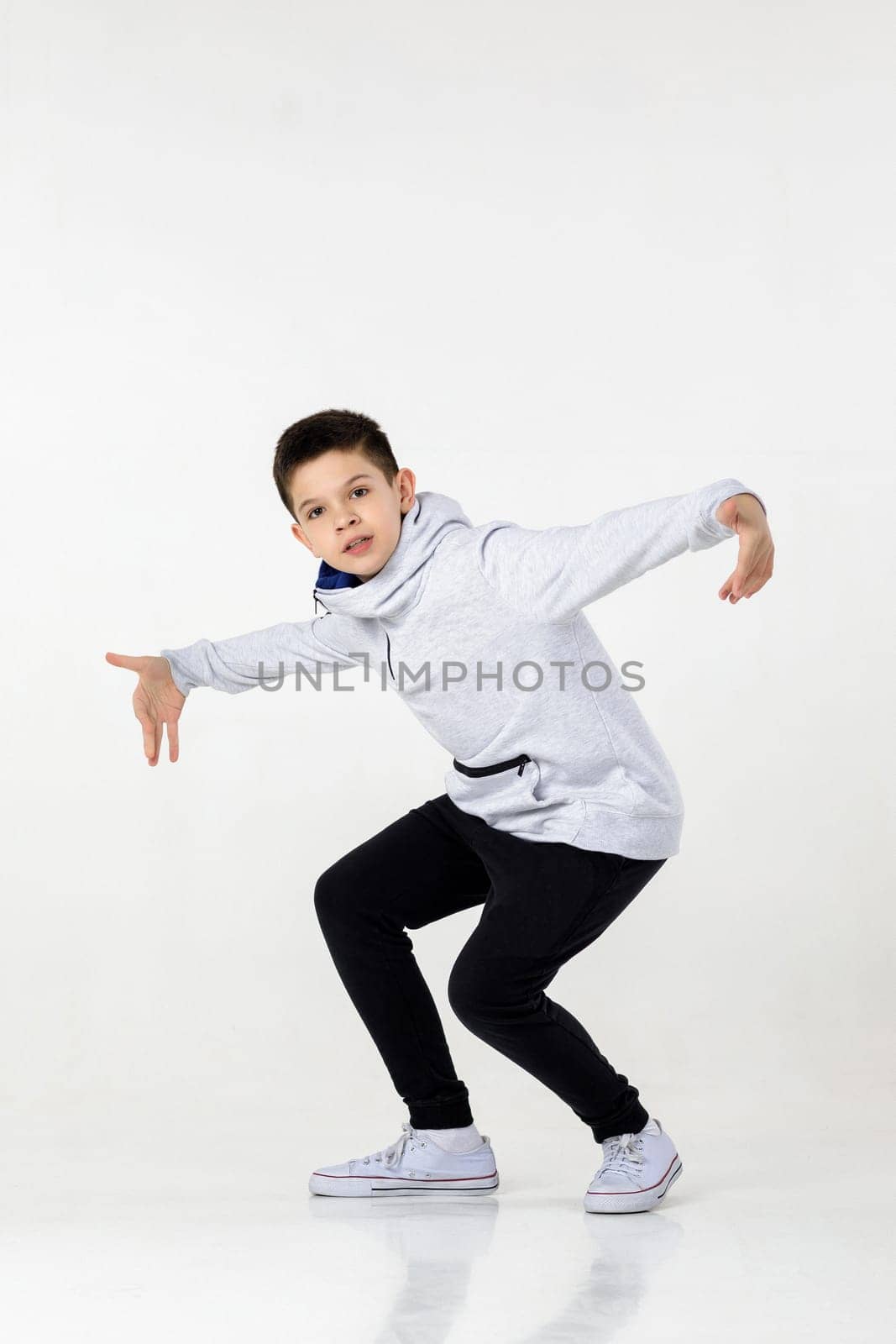 Little hip-hop boy dancing on white studio background. sports dance. modern style