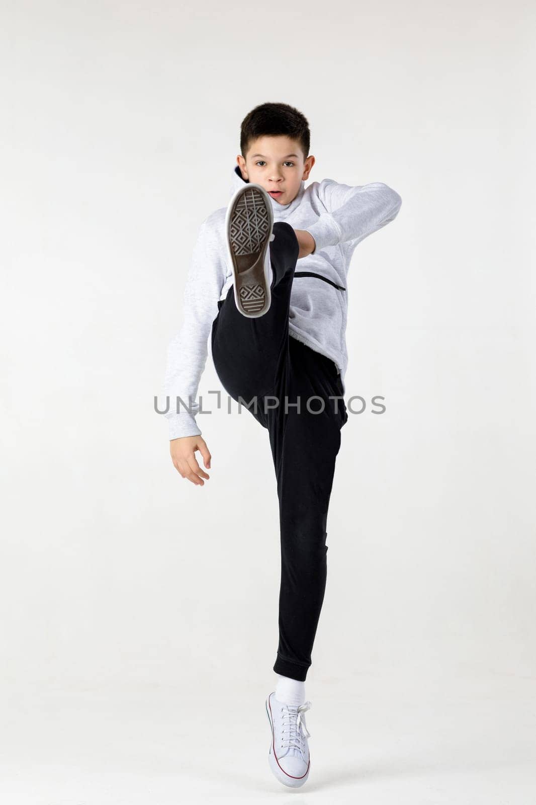 Little hip-hop boy dancing on white studio background.