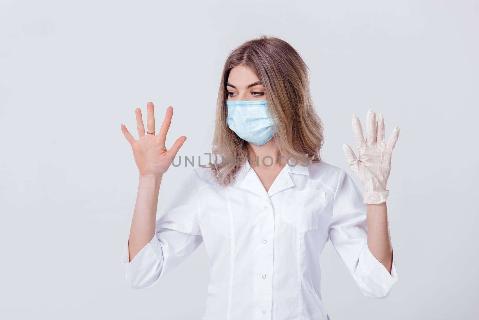 Portrait of woman doctor with face mask doctor shows hands. one gloved hand and the other without