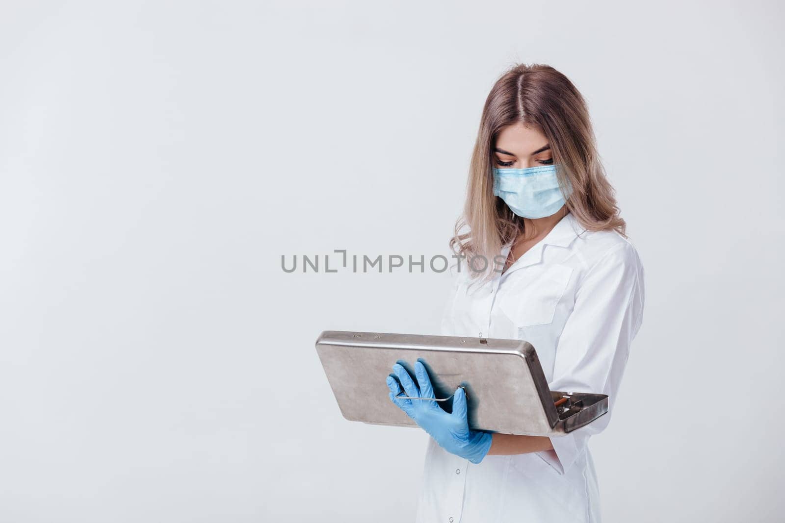 Portrait of woman doctor with face mask and medical gloves holds a metal bag with medical instruments