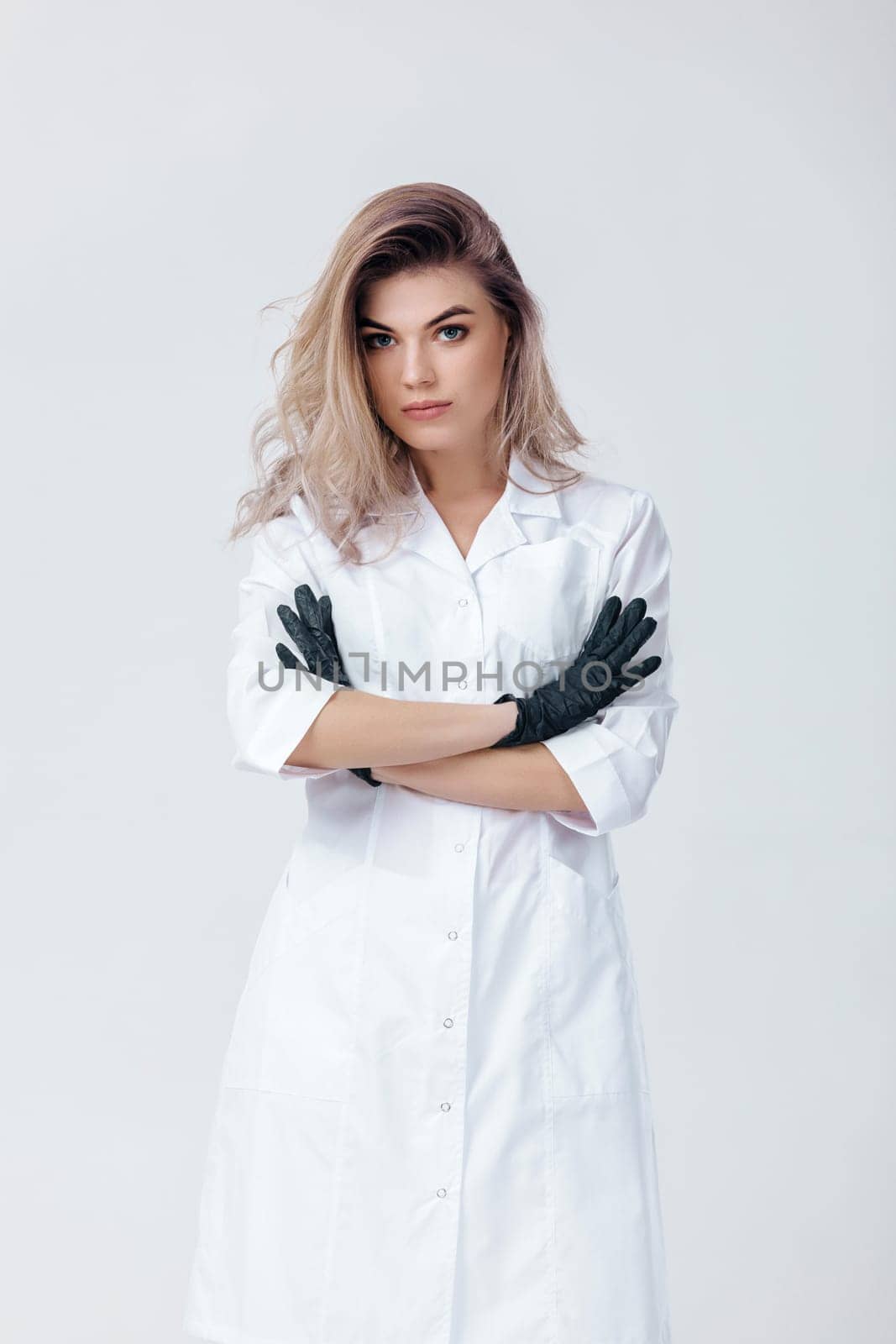Portrait of young female professional cosmetologist in black gloves. Woman beautician doctor in studio