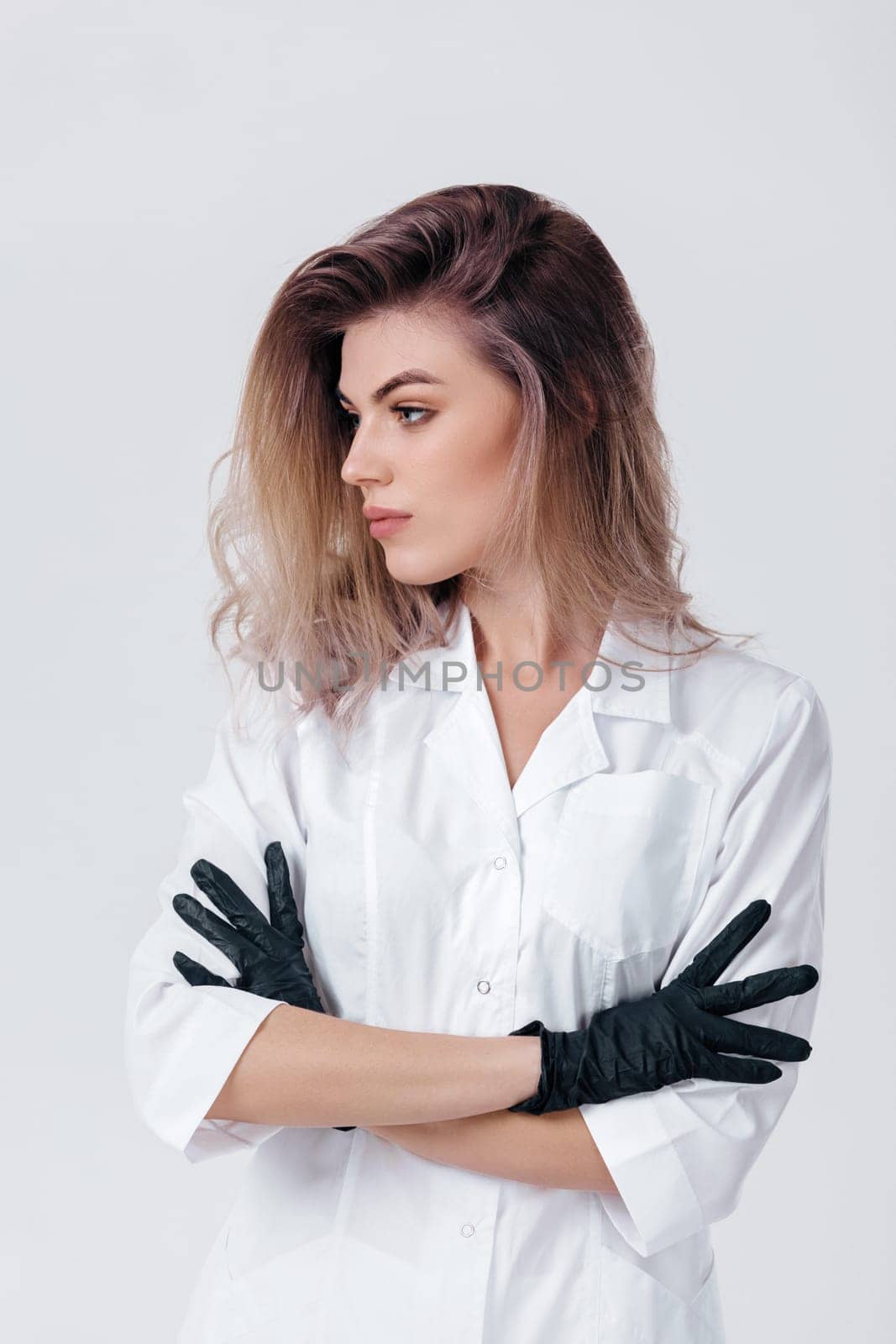 Portrait of young female professional cosmetologist in black gloves. Woman beautician doctor in studio