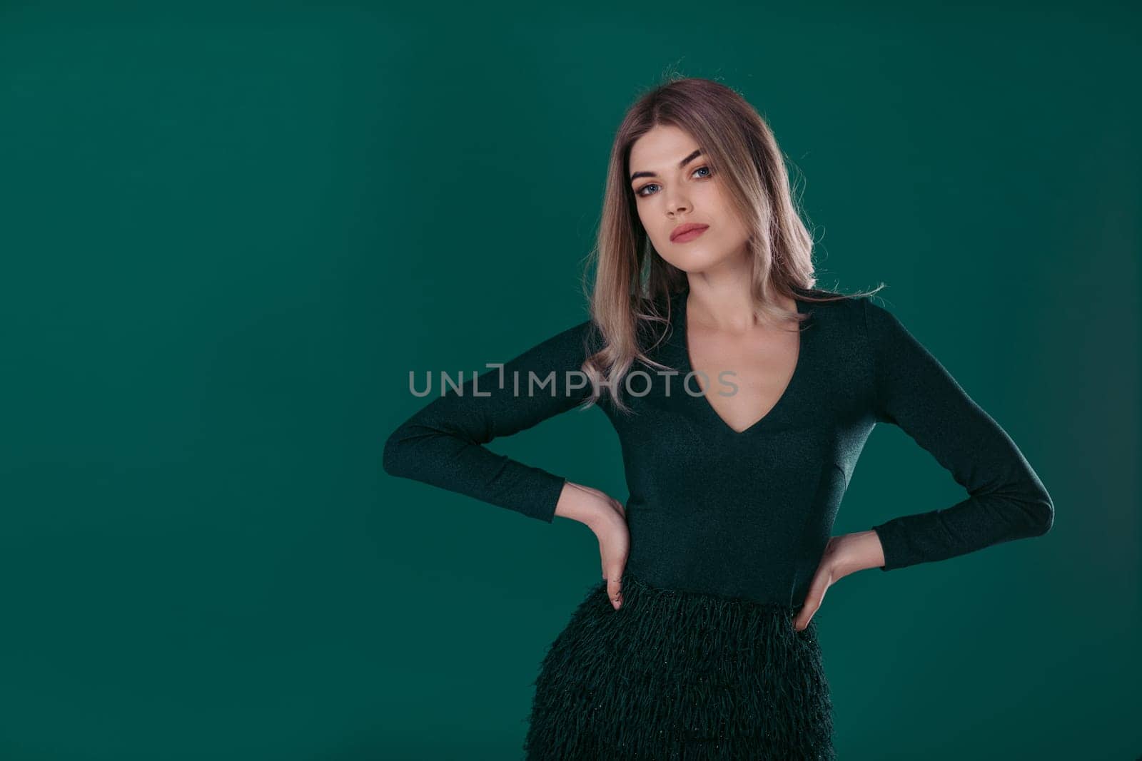 beautiful blonde woman posing in green dress on green background. space for text