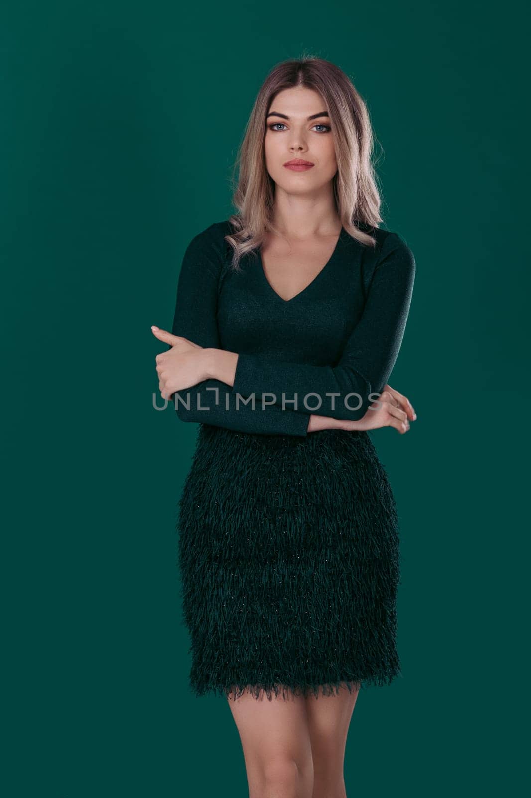 calm beautiful blonde woman posing in green dress on green background