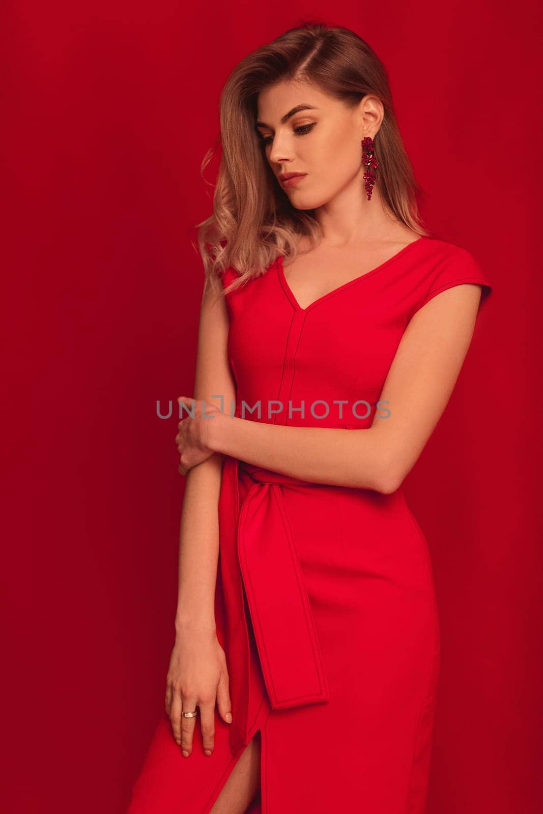 Sensual sexy beautiful blonde woman posing in red dress on red background