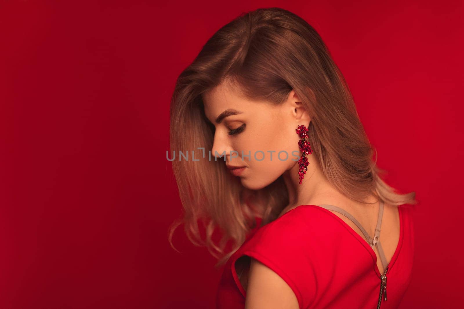 Sensual sexy beautiful blonde woman posing in red dress on red background