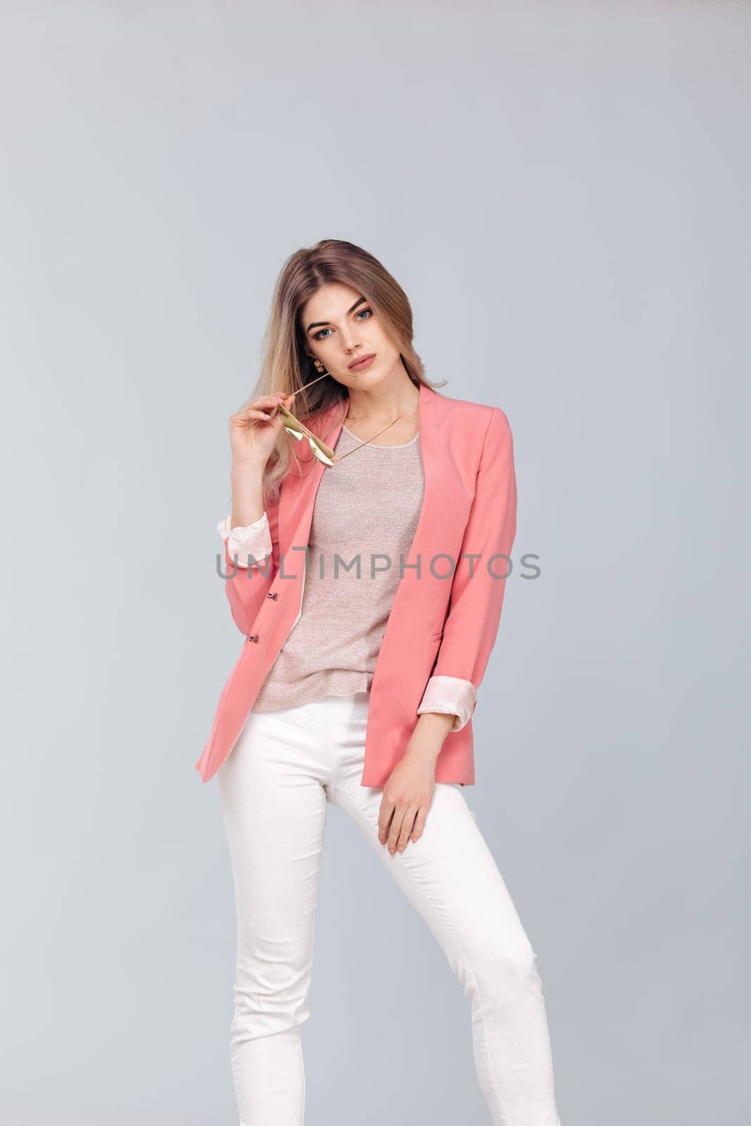 Fashion portrait of attractive elegant blonde woman in pastel casual pink jacket posing in studio. woman dressed in trendy spring outfit