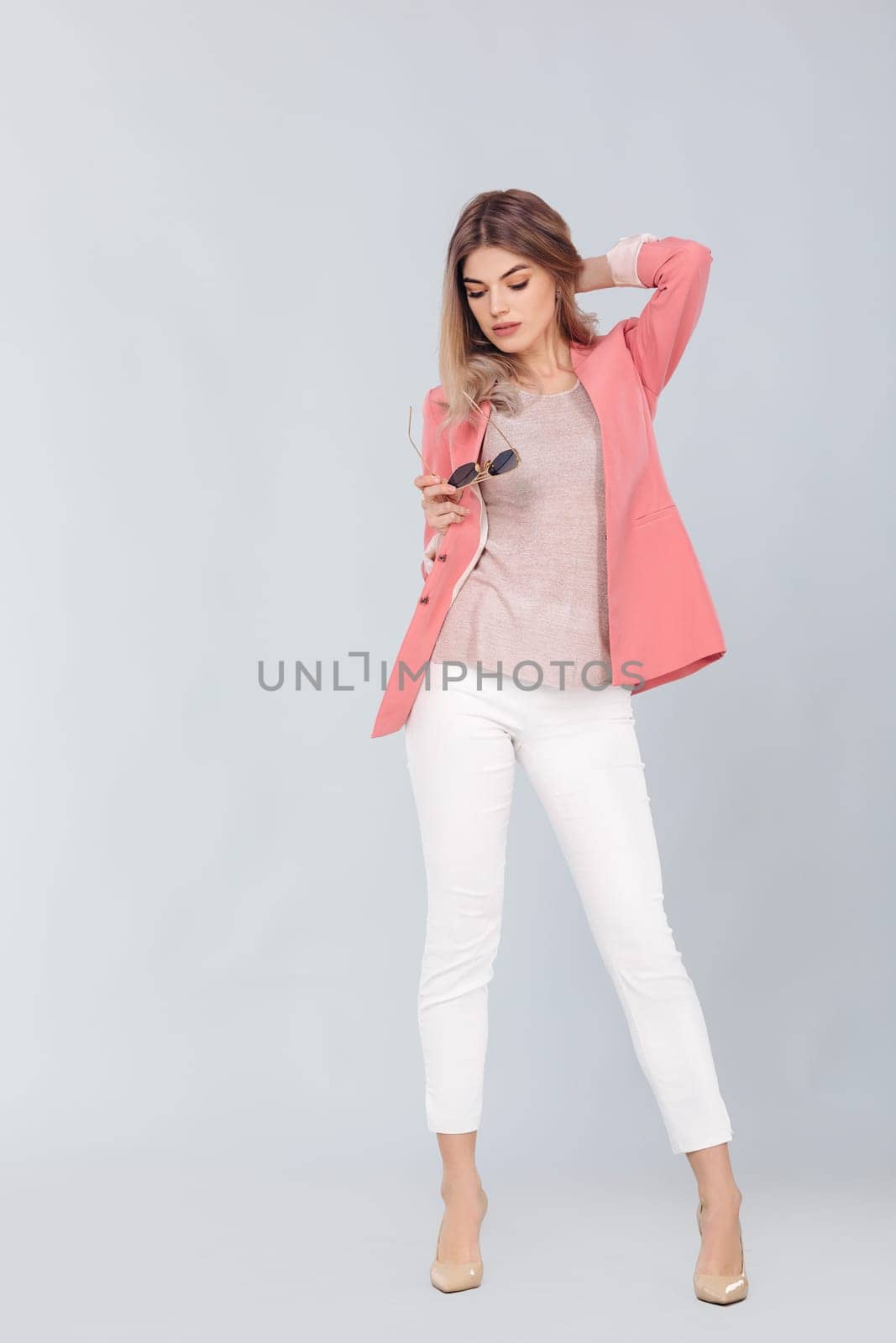 Full length portrait of attractive elegant blonde woman in pastel pink jacket posing in studio. woman dressed in trendy spring outfit