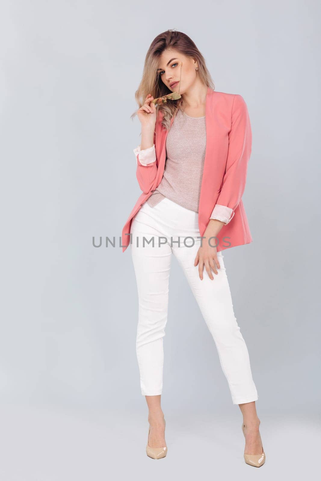 blonde woman in pastel casual jacket posing in studio. by erstudio