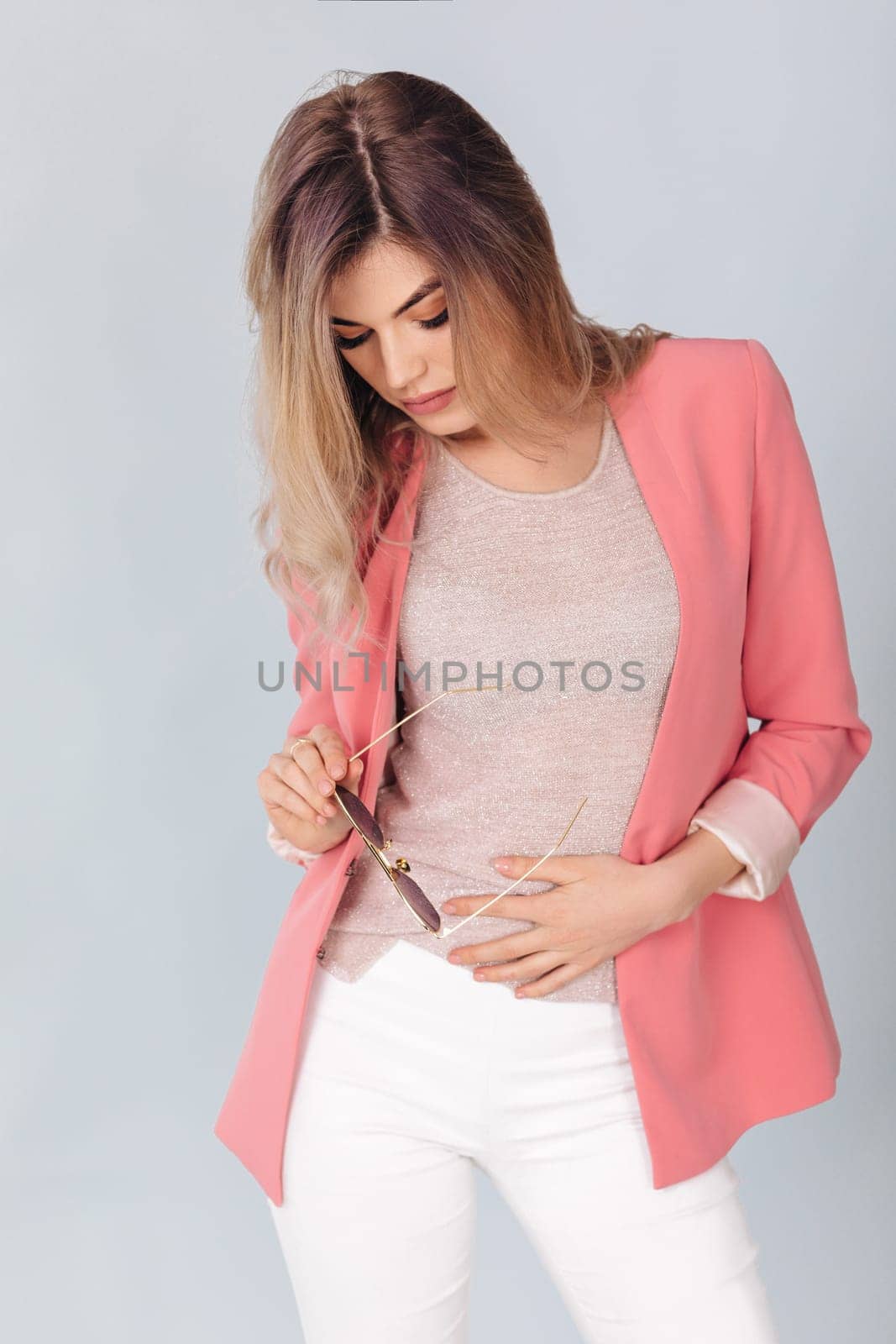 Fashion portrait of attractive elegant blonde woman in pastel casual pink jacket posing in studio. woman dressed in trendy spring outfit