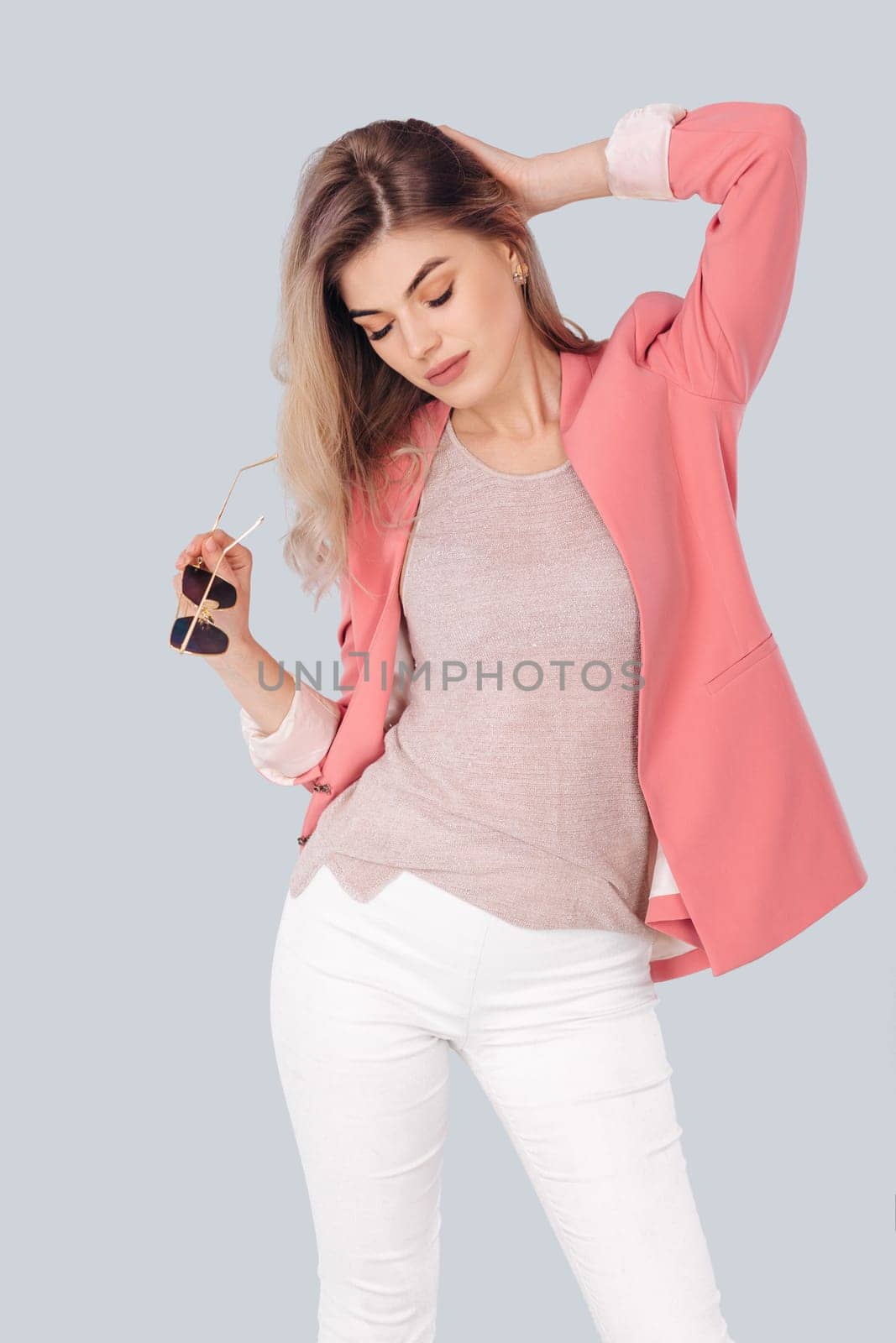 Fashion portrait of attractive elegant blonde woman in pastel casual pink jacket posing in studio. woman dressed in trendy spring outfit