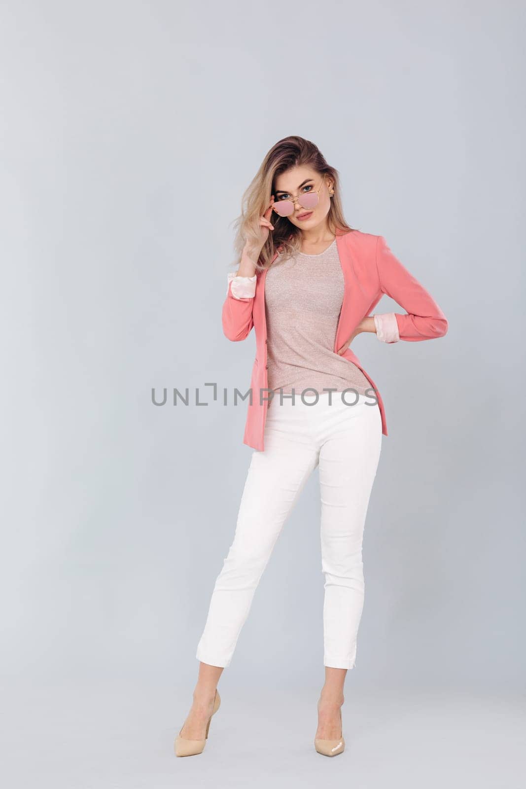 Full length portrait of attractive elegant blonde woman in pastel pink jacket posing in studio. woman dressed in trendy spring outfit
