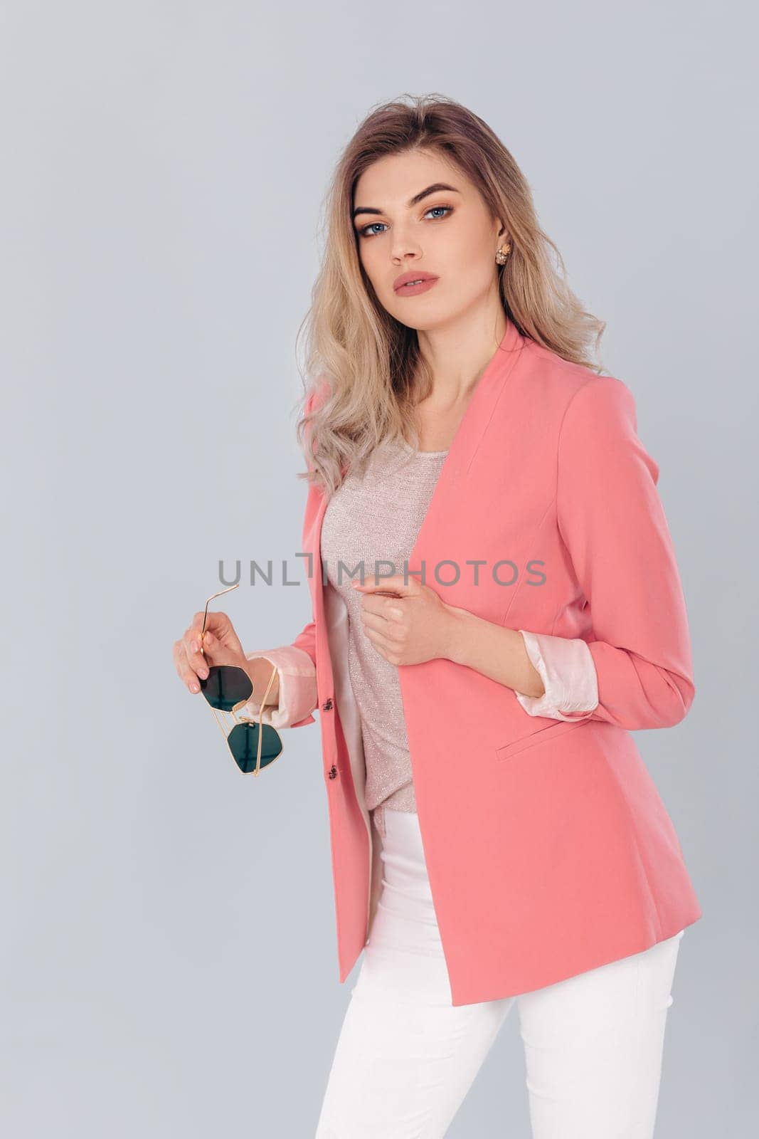 blonde woman in pastel casual jacket posing in studio. by erstudio
