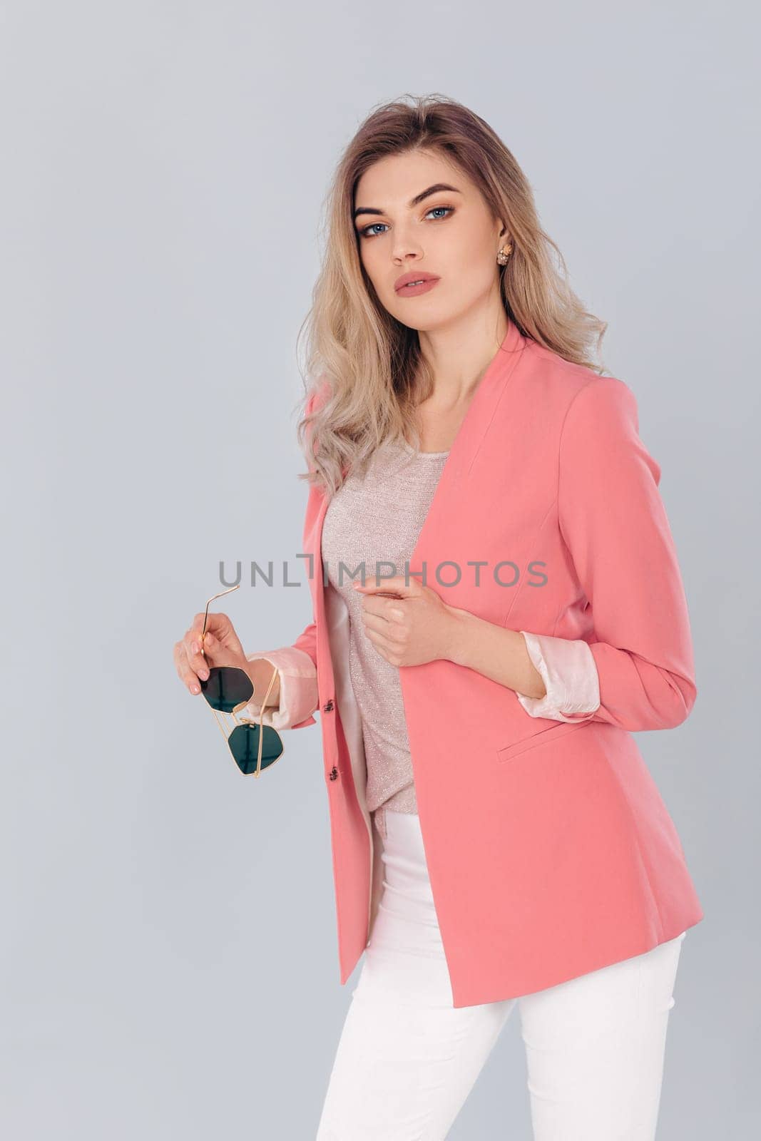 Fashion portrait of attractive elegant blonde woman in pastel casual pink jacket posing in studio. woman dressed in trendy spring outfit