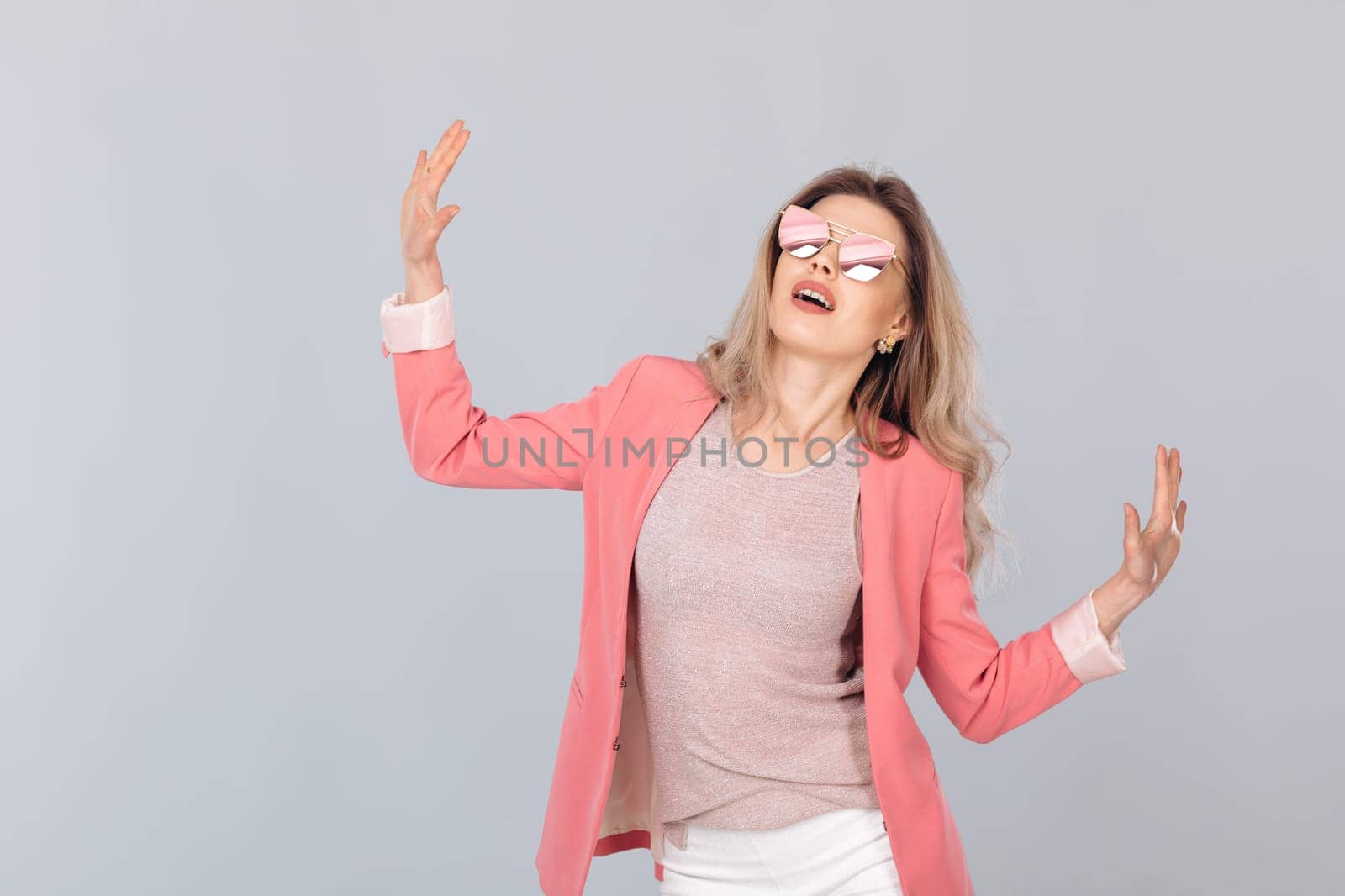 Fashion portrait of attractive elegant blonde woman in pastel jacket and sunglasses dancing. woman dressed in trendy spring outfit