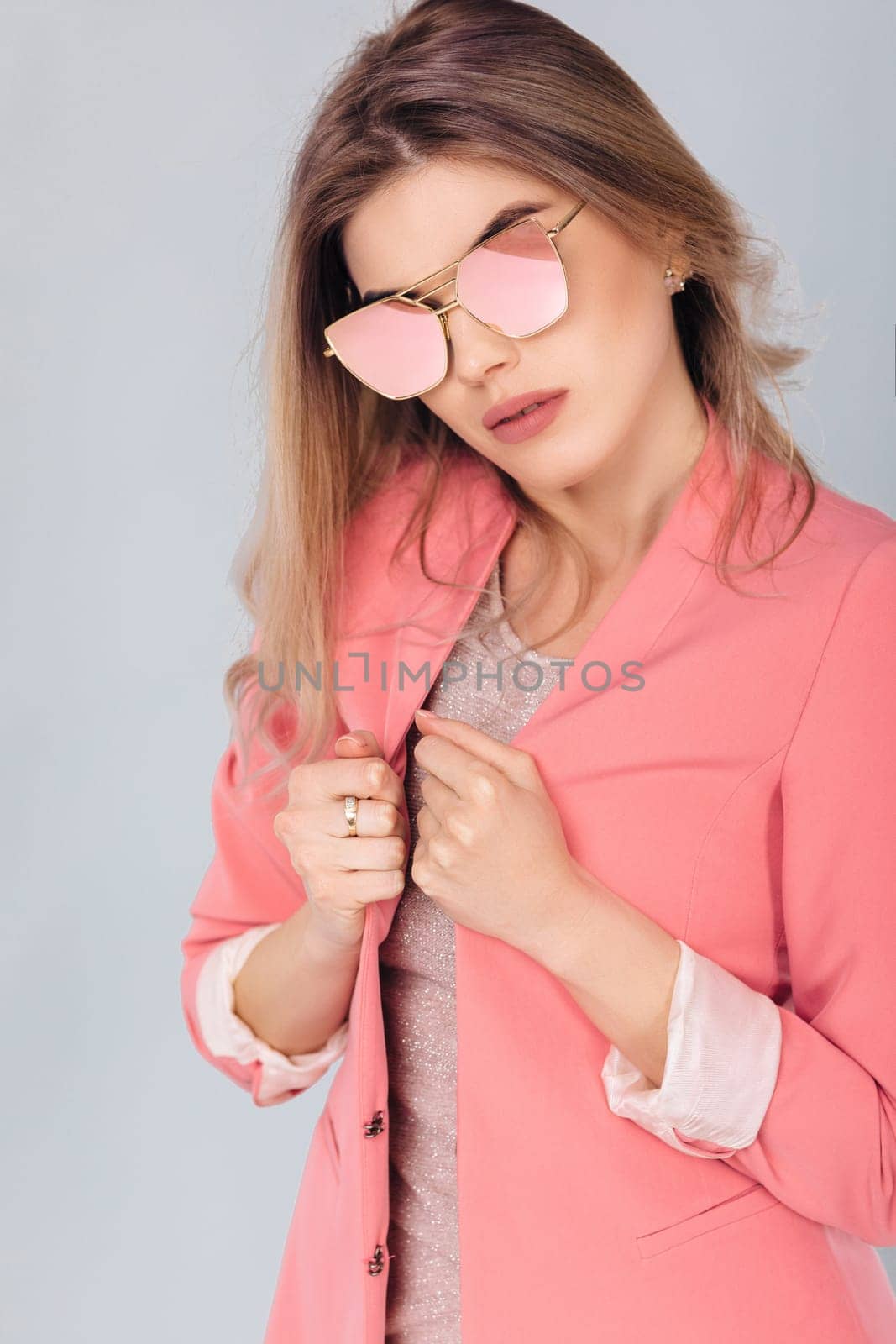 Fashion portrait of attractive elegant blonde woman in pastel pink jacket and sunglasses posing in studio. woman dressed in trendy spring outfit