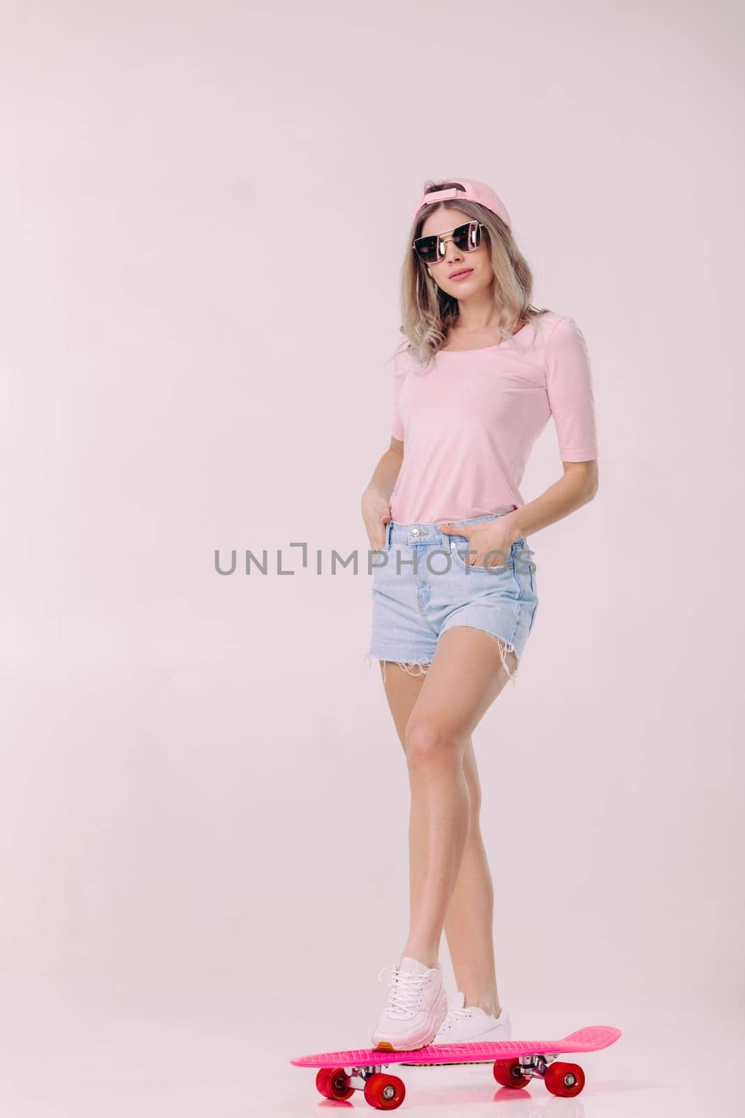 beautiful woman in sunglasses, pink t-shirt and cap with pink skateboard