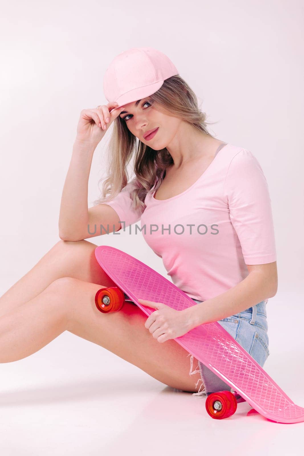 beautiful woman in white t-shirt with pink skateboard by erstudio
