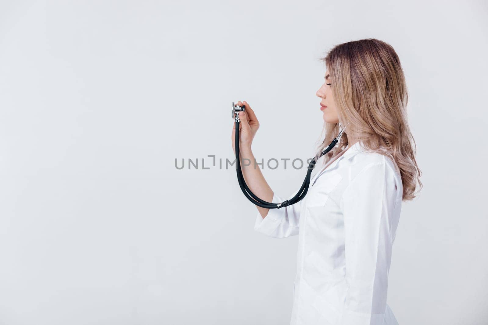 Medical physician doctor woman in white coat examining with stethoscope on light background.