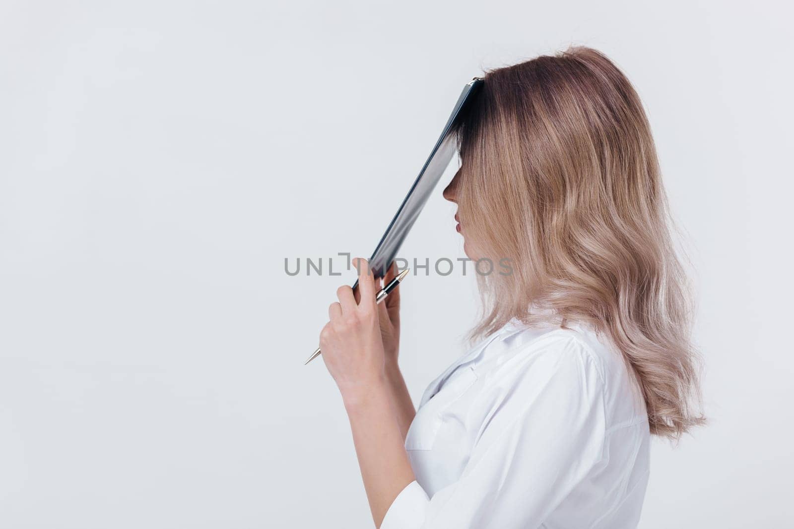 sad medical physician doctor woman in white coat holds folder with documents on light background.