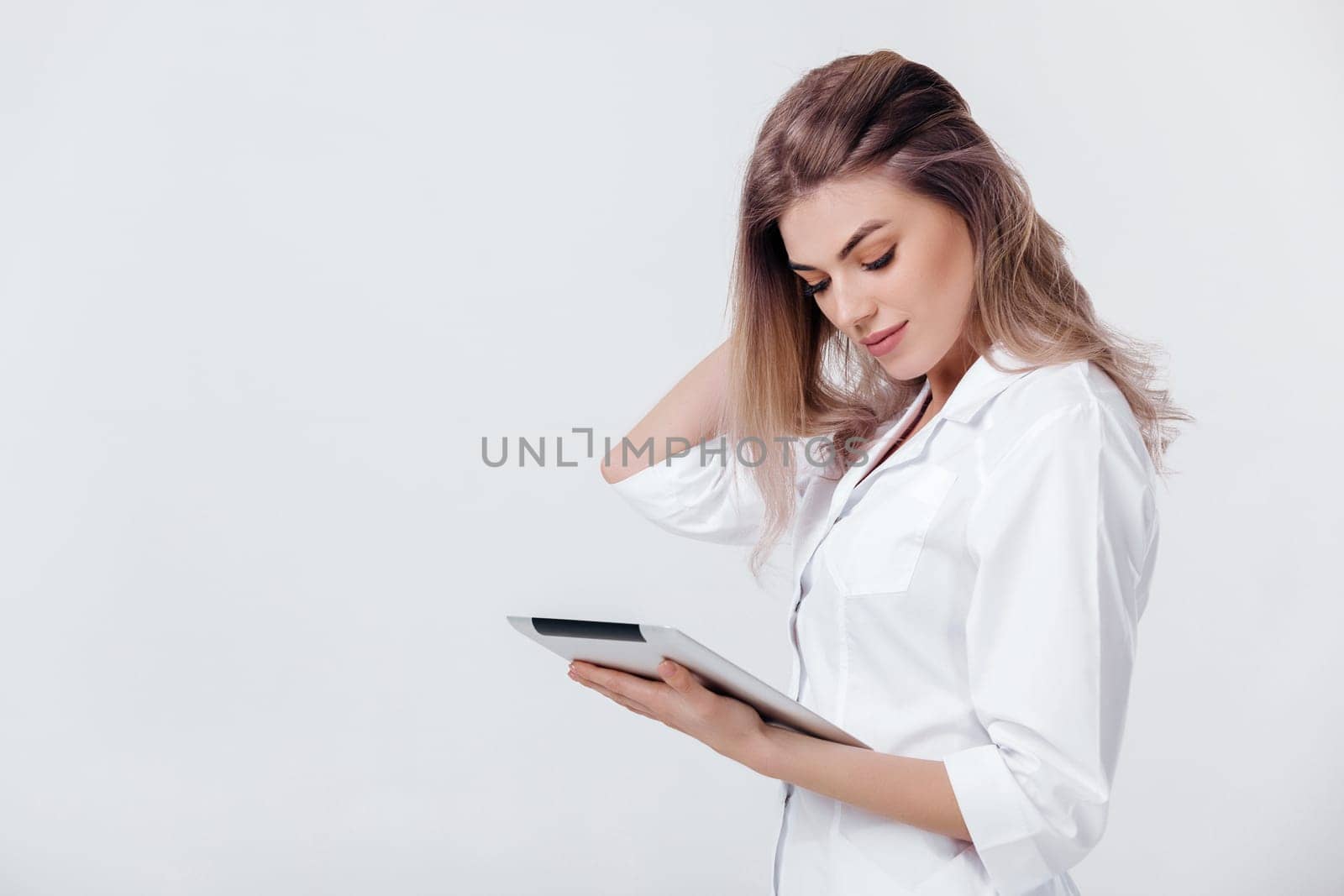 beautiful blonde doctor in white coat using digital tablet by erstudio