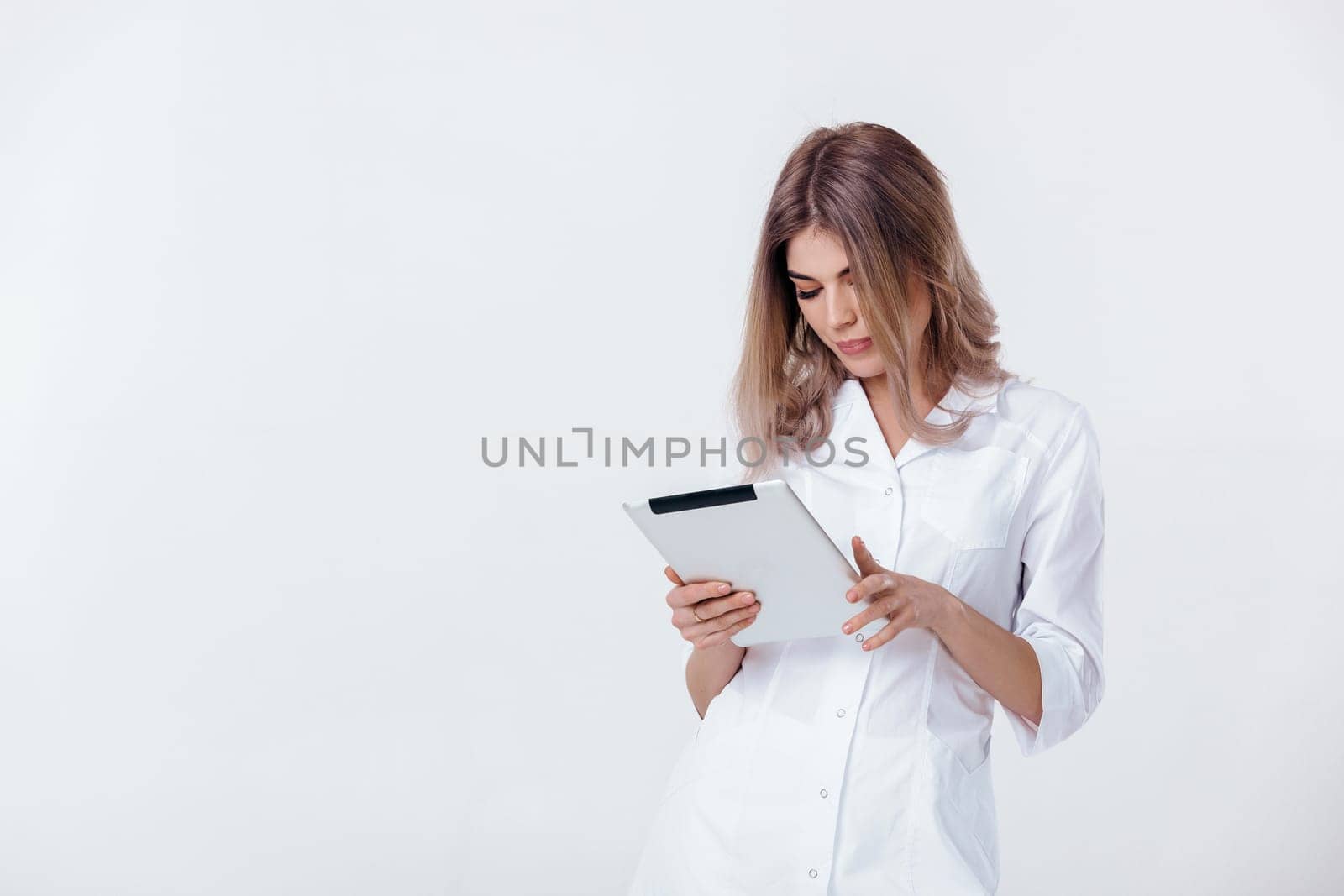 beautiful blonde doctor in white coat using digital tablet by erstudio