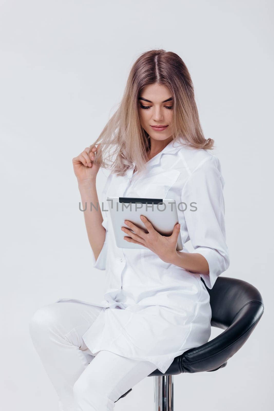 Portrait of beautiful blonde doctor in white coat using digital tablet