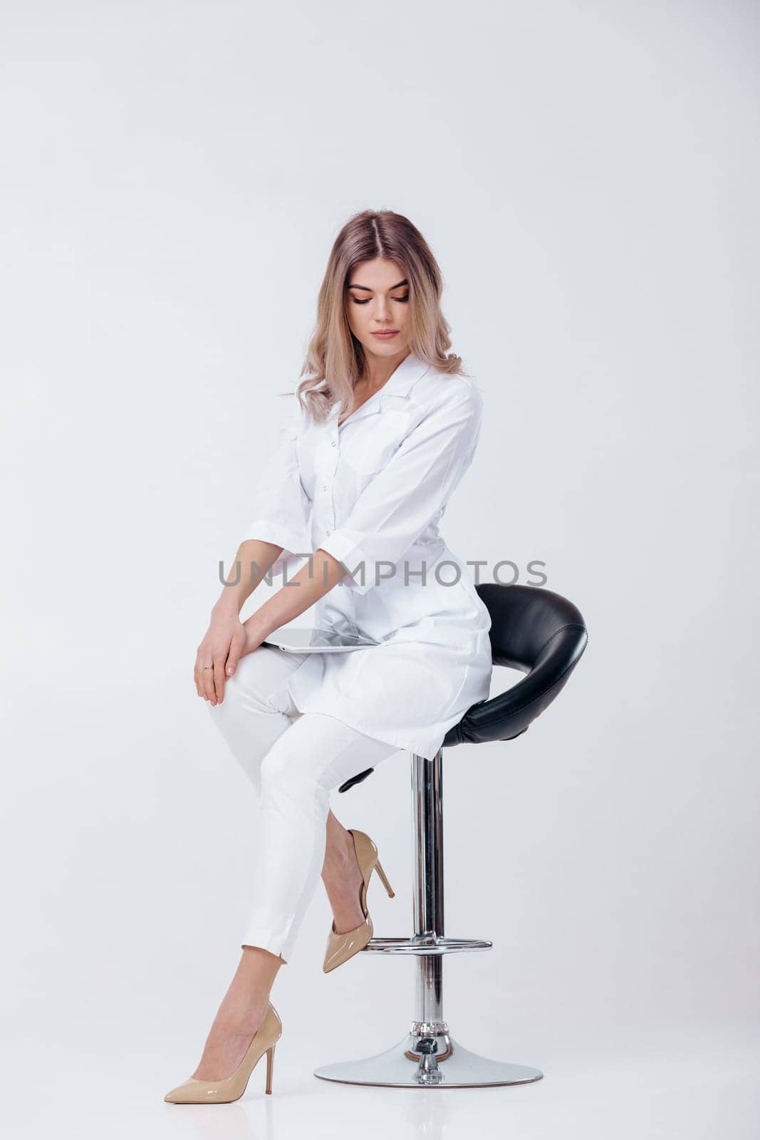 beautiful blonde doctor in white coat using digital tablet by erstudio