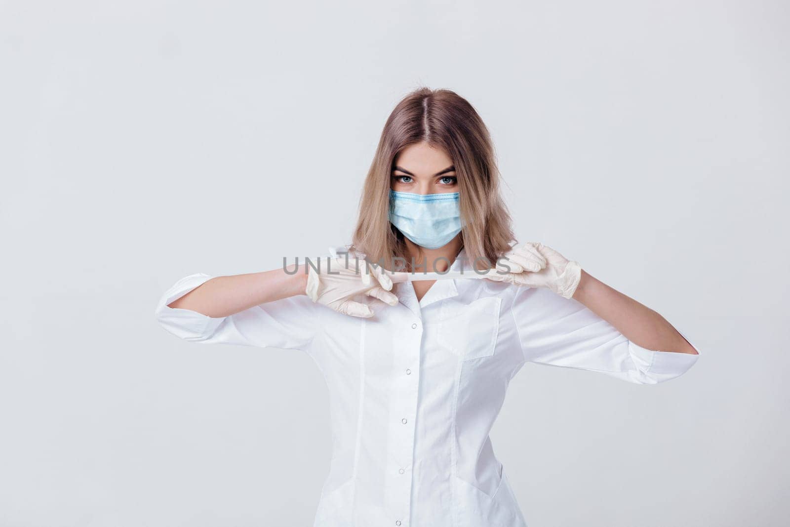 Portrait of woman doctor with face mask takes off white medical gloves