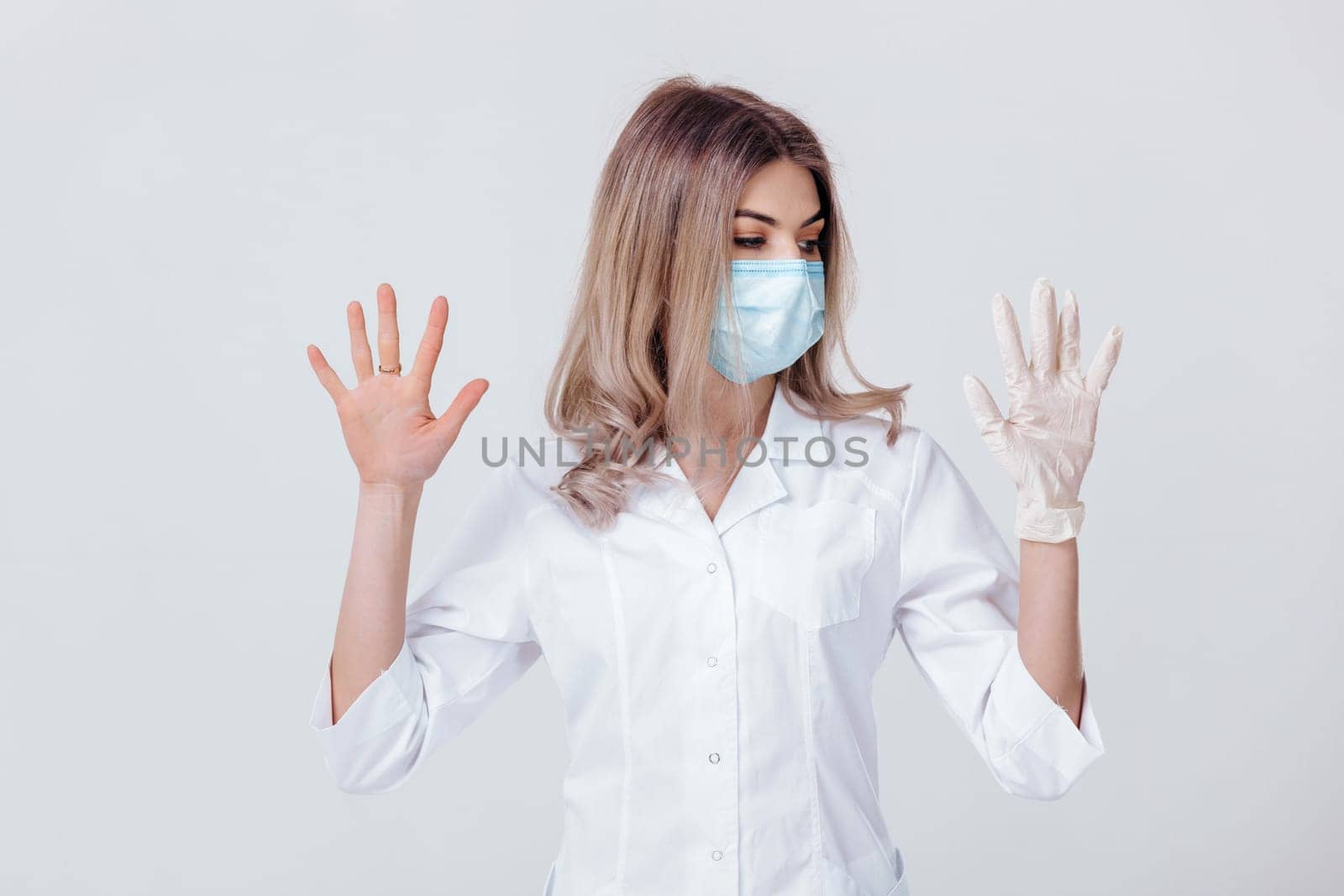 Portrait of woman doctor with face mask doctor shows hands. one gloved hand and the other without