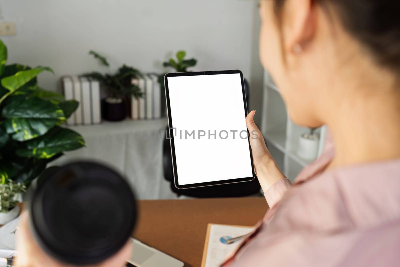 businesswoman hold mockup digital tablet with blank screen Mockup replace your design mockup in the office.