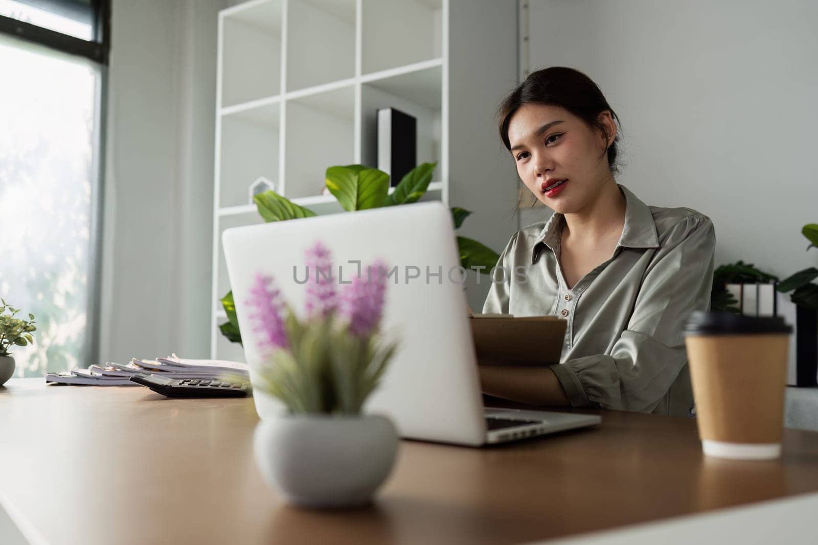 business woman working with laptop while consulting some invoice and document in working space at home.