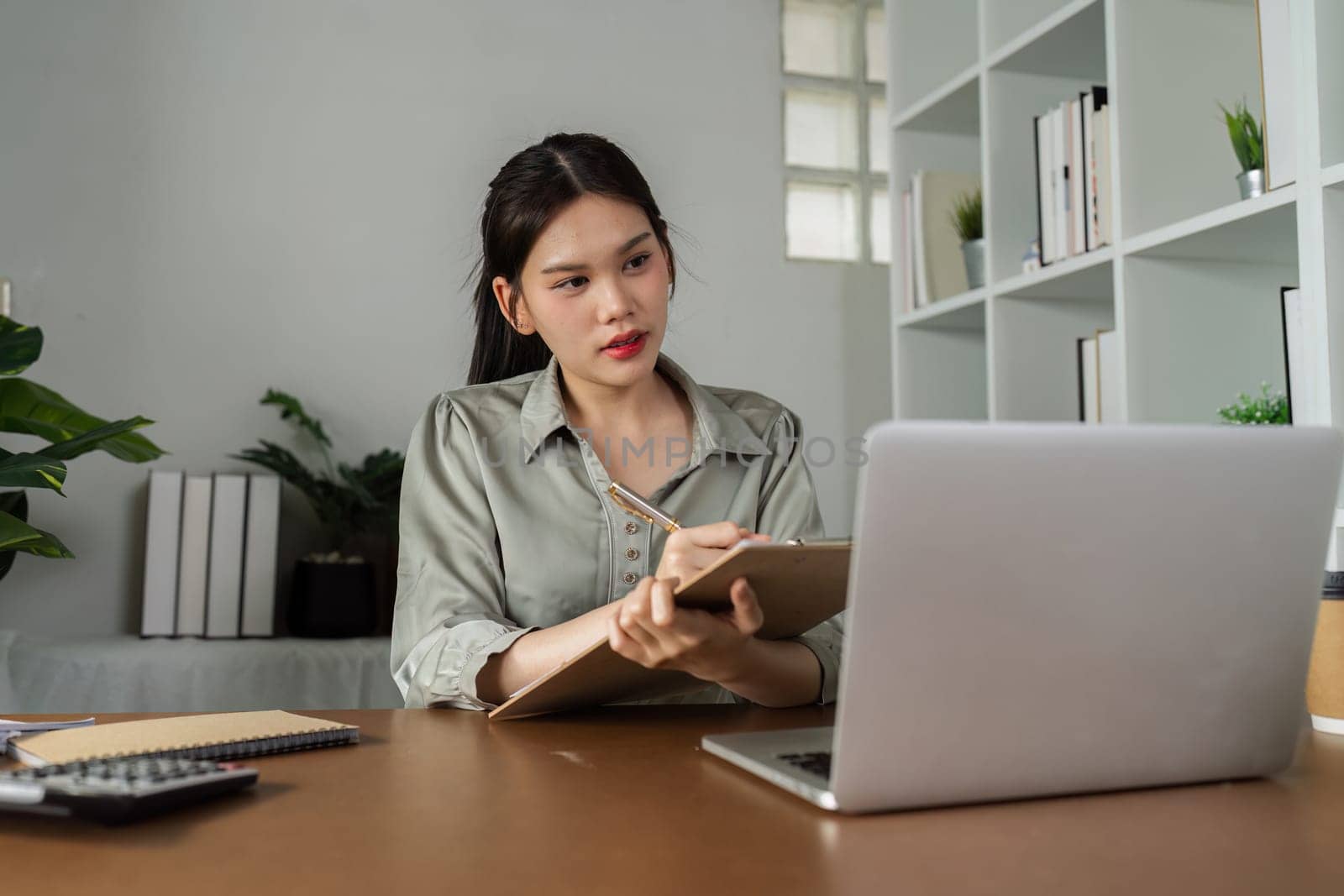 business woman working with laptop while consulting some invoice and document in working space at home by itchaznong