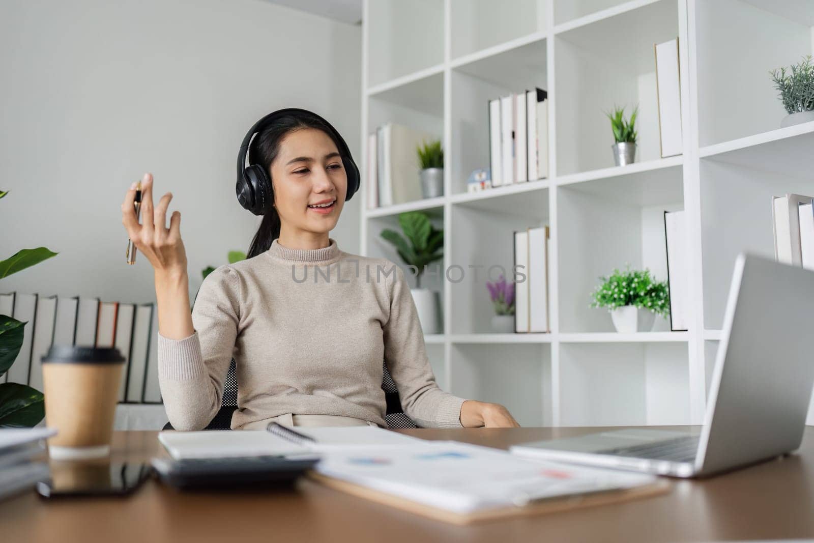 Young Asian business woman employee or executive manager using laptop and talking leading hybrid conference remote video call or online training working in office.