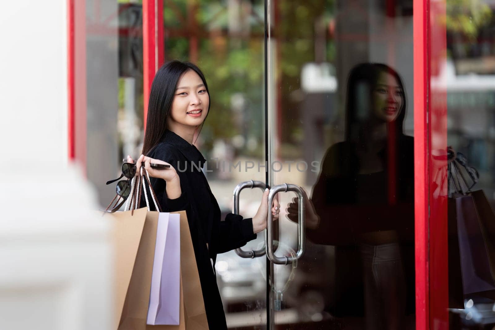 Cheerful Beautiful Asian woman holding shopping bags in shopping in the city on holiday Black Friday.