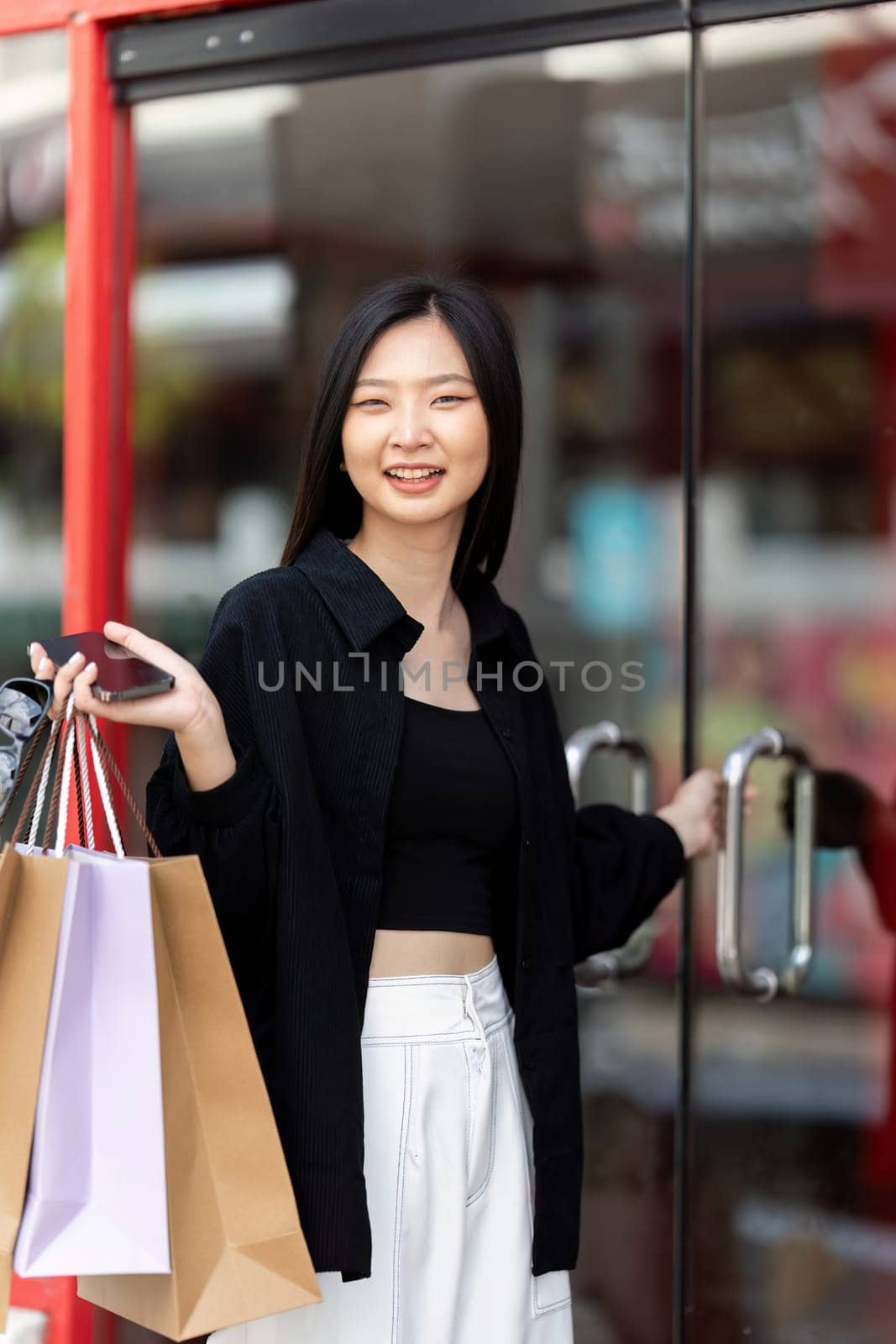 Cheerful Beautiful Asian woman holding shopping bags in shopping in the city on holiday Black Friday by nateemee