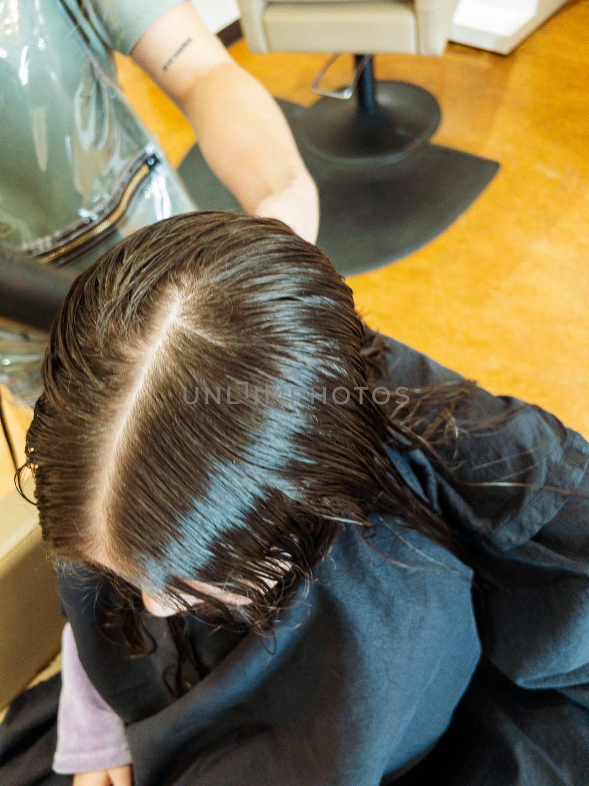 Gentle hands maneuver a hair dryer through a young girl's newly cut hair, showcasing the drying process after a meticulous trim. The warmth of the dryer breathes life into her locks, as they transform from damp to styled with care and expertise.