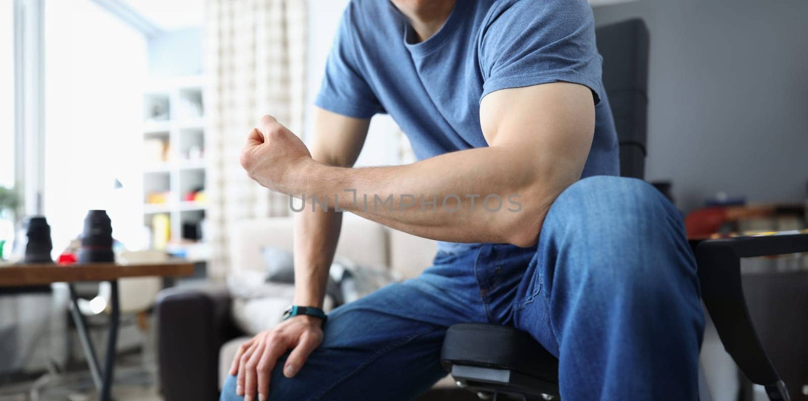 Man bending his arm and straining his biceps closeup by kuprevich