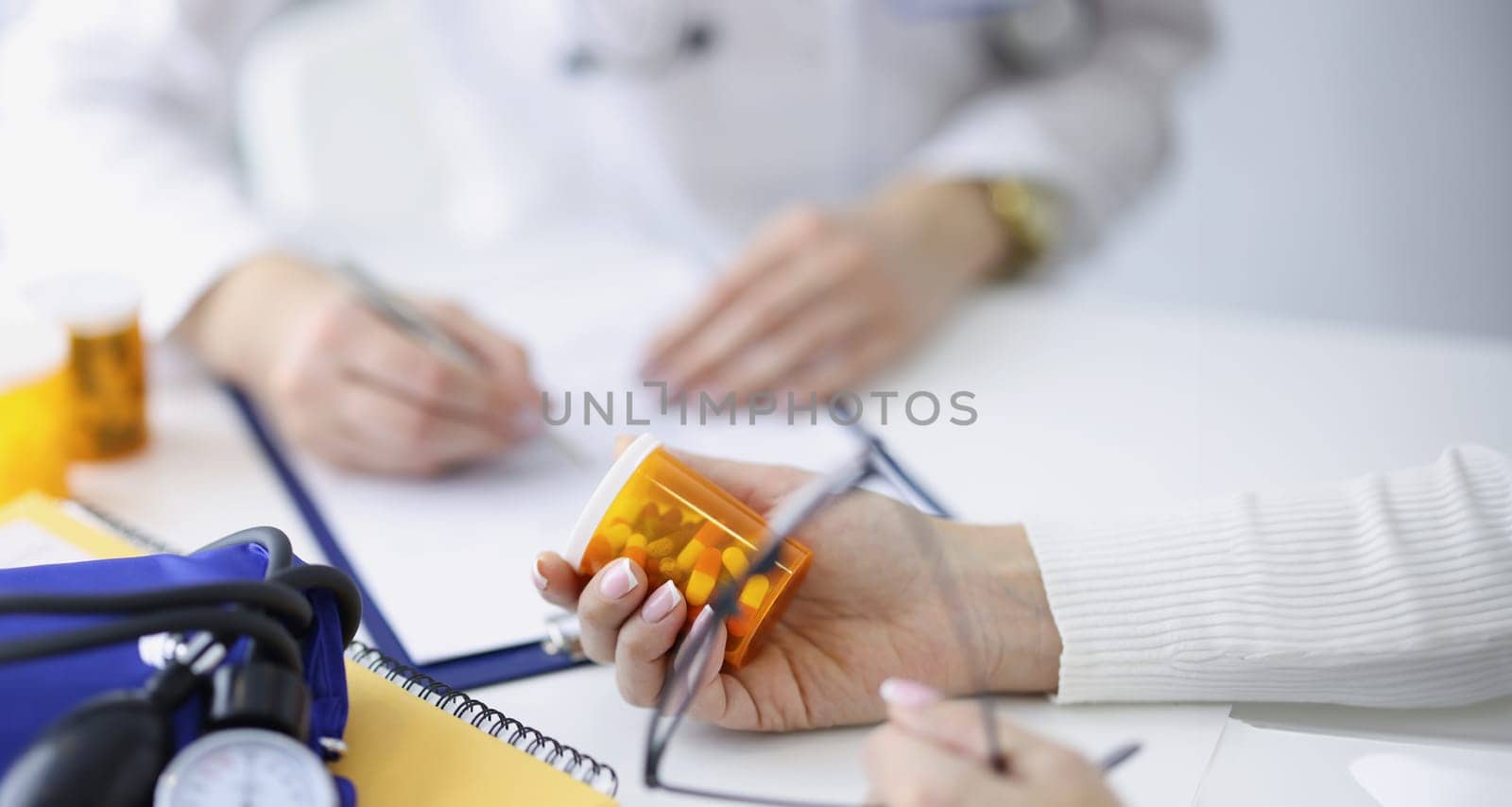 Patient holding jar of medicines in his hands against background of doctor closeup. Prescription drug dispensing concept