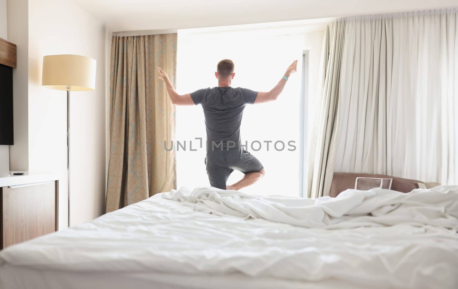 Man doing yoga in front of window in morning. Meditation concept