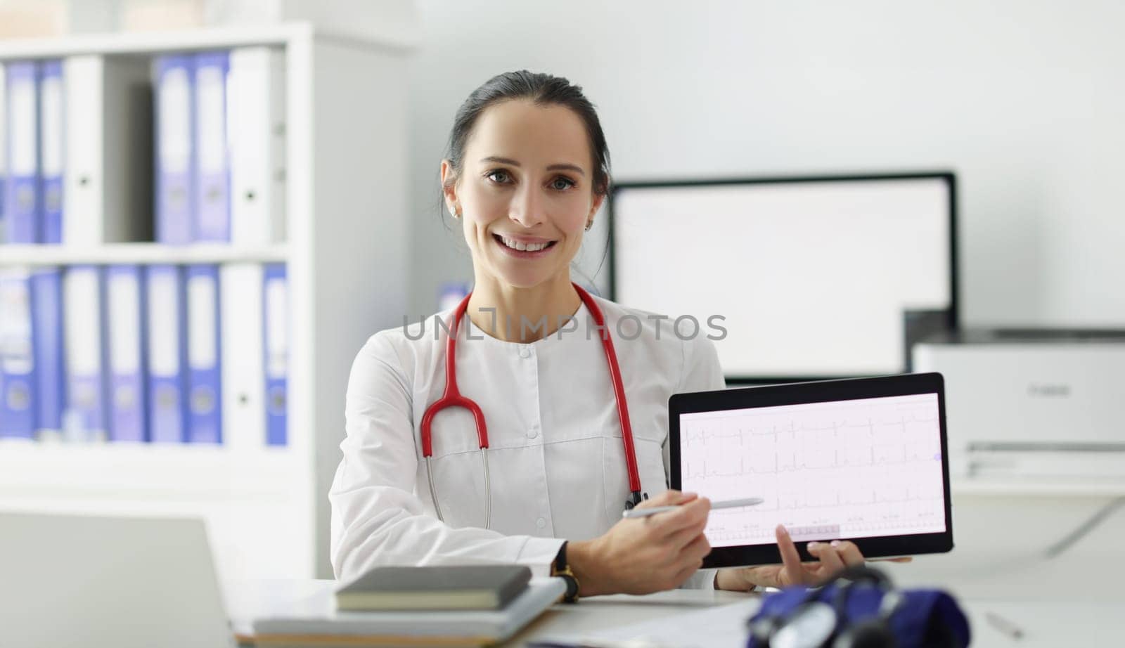 Doctor cardiologist showing electrocardiogram on digital tablet by kuprevich