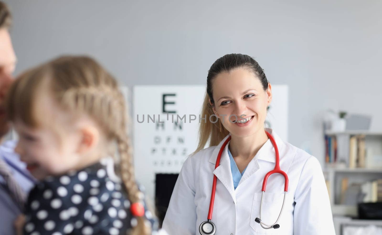 Smiling female doctor standing near little girl in clinic by kuprevich