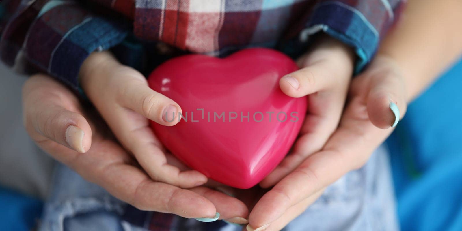 Woman and child hands holding red toy heart closeup by kuprevich