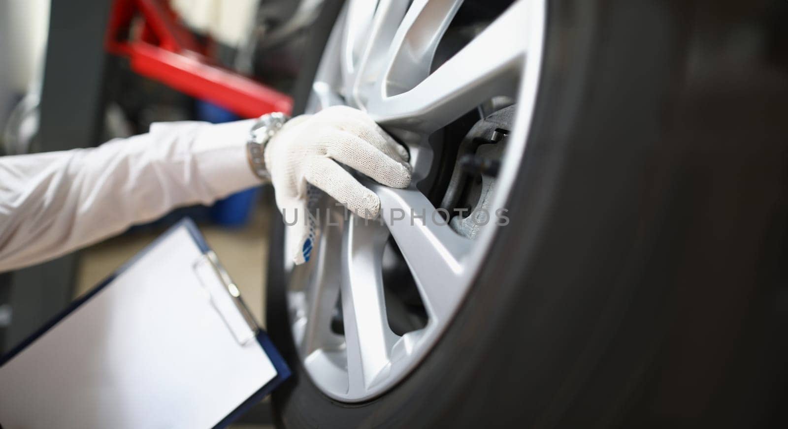 Master repairman holding documents and looking at quality of tires closeup. Car breakdown diagnostics concept